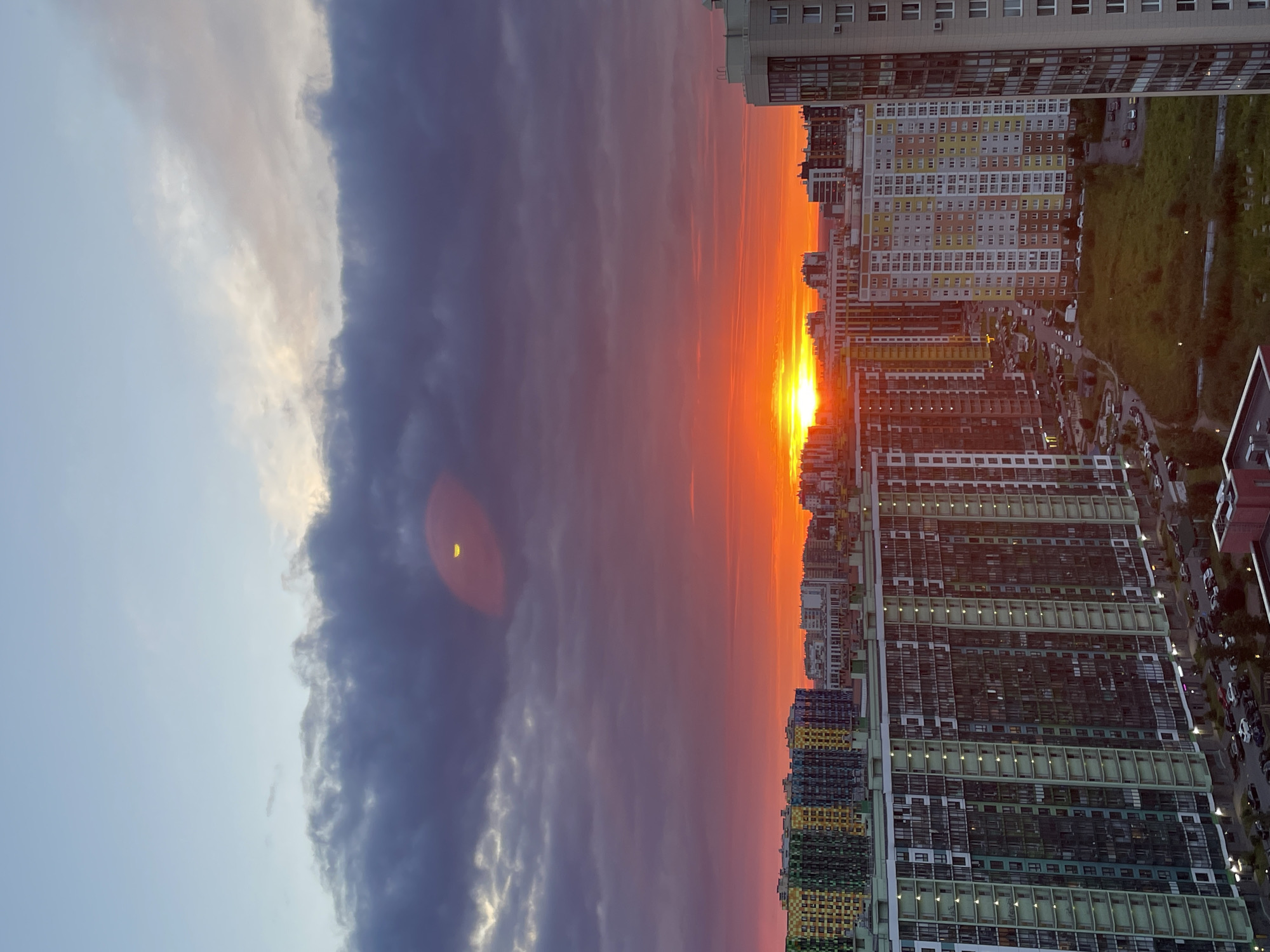 City skyline framed by a vivid, crescent-moon sunset