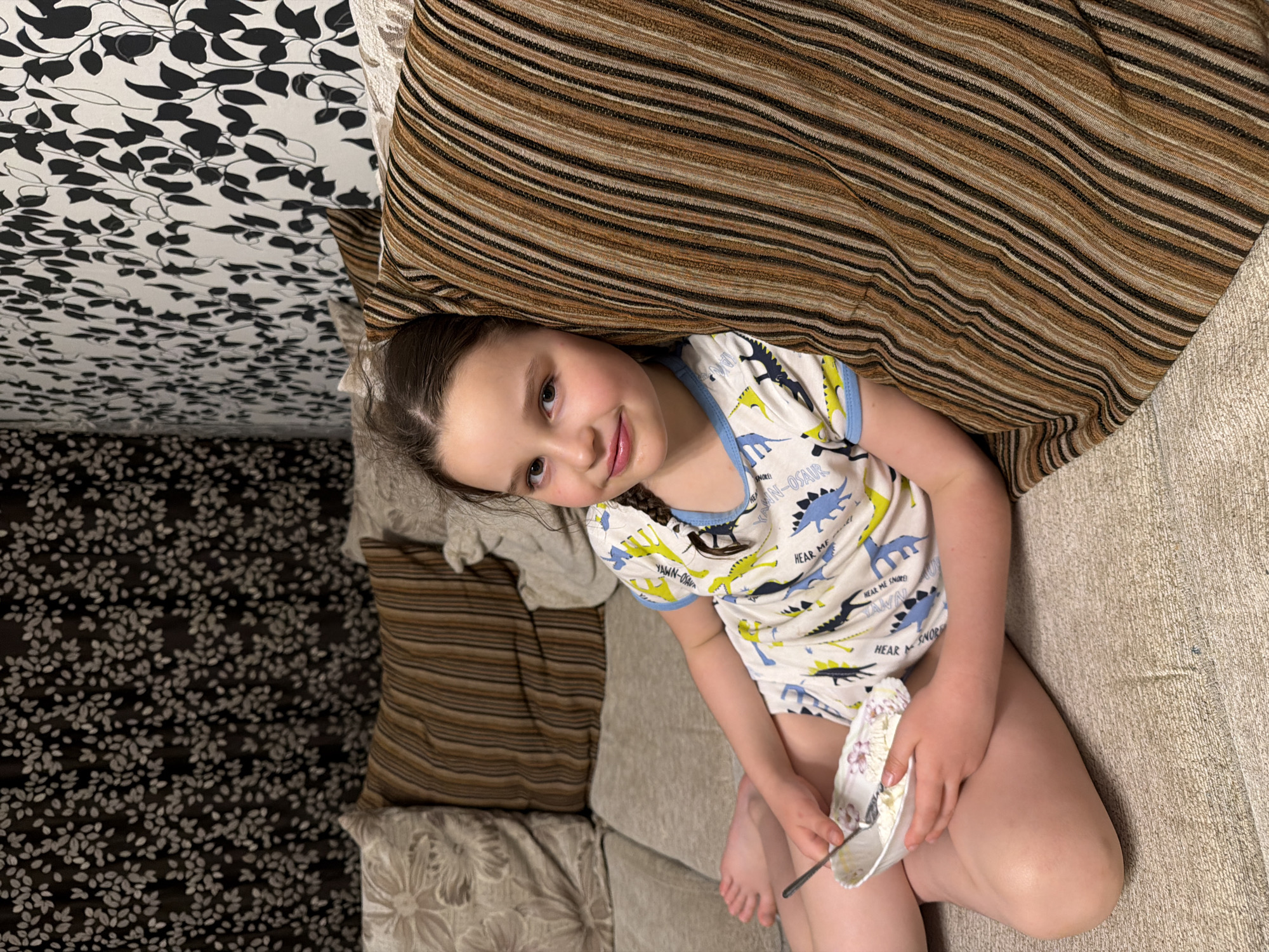 Child enjoys meal on couch in Russian home