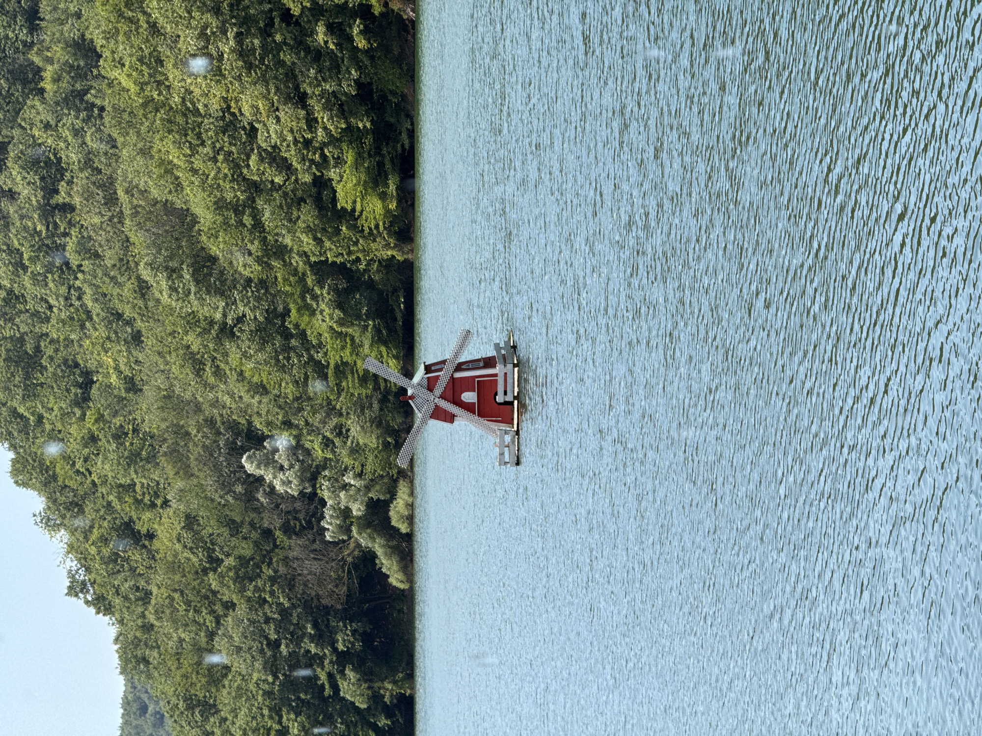 Quiet lakeside scene with wooden structures and a decorative windmill, Şile