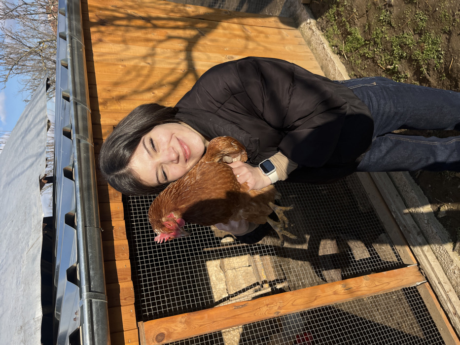 Young woman tends chickens in Bulgarian village yard