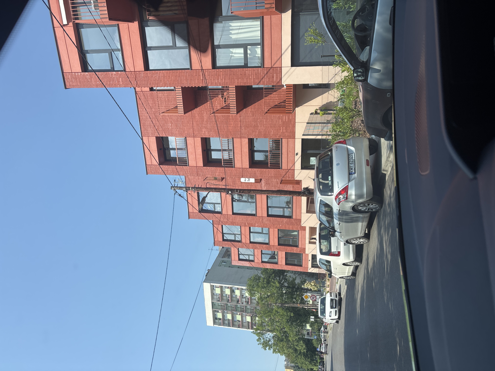 Driving through a quiet Kraków neighborhood past shops and parcel lockers