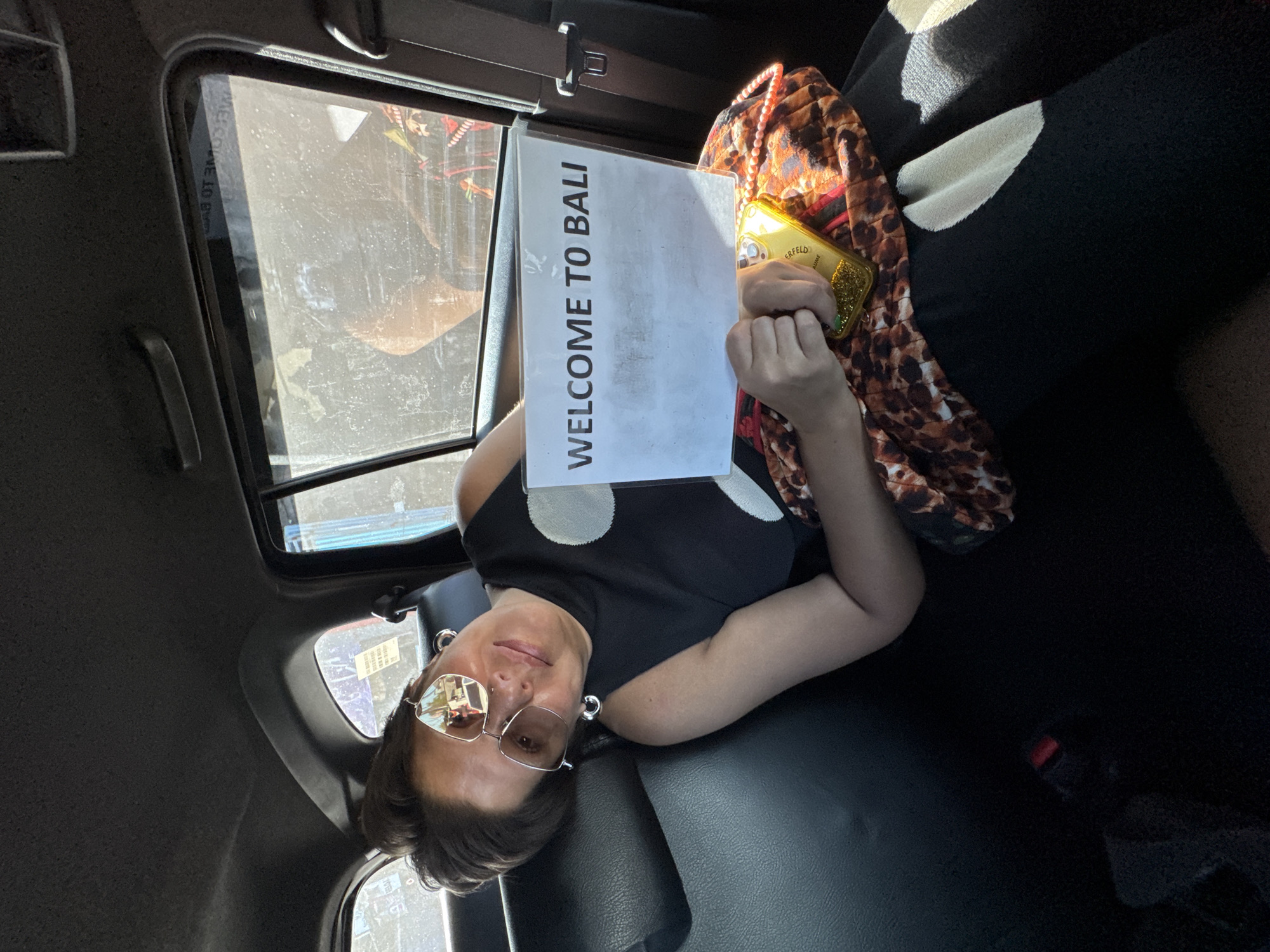 Tourist holds welcome sign in vehicle in Bali