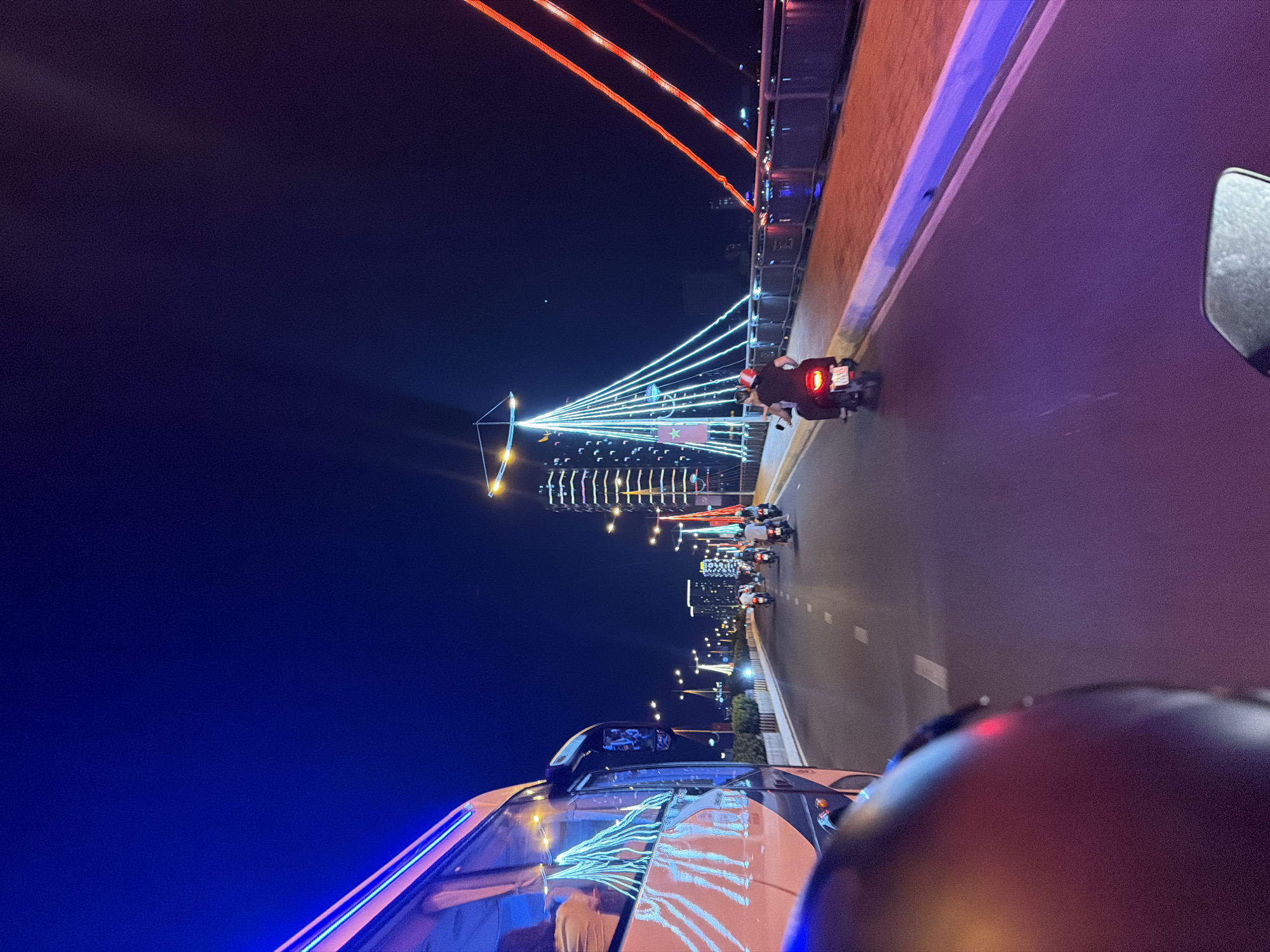 Nighttime traffic observed near illuminated bridge in Nha Trang