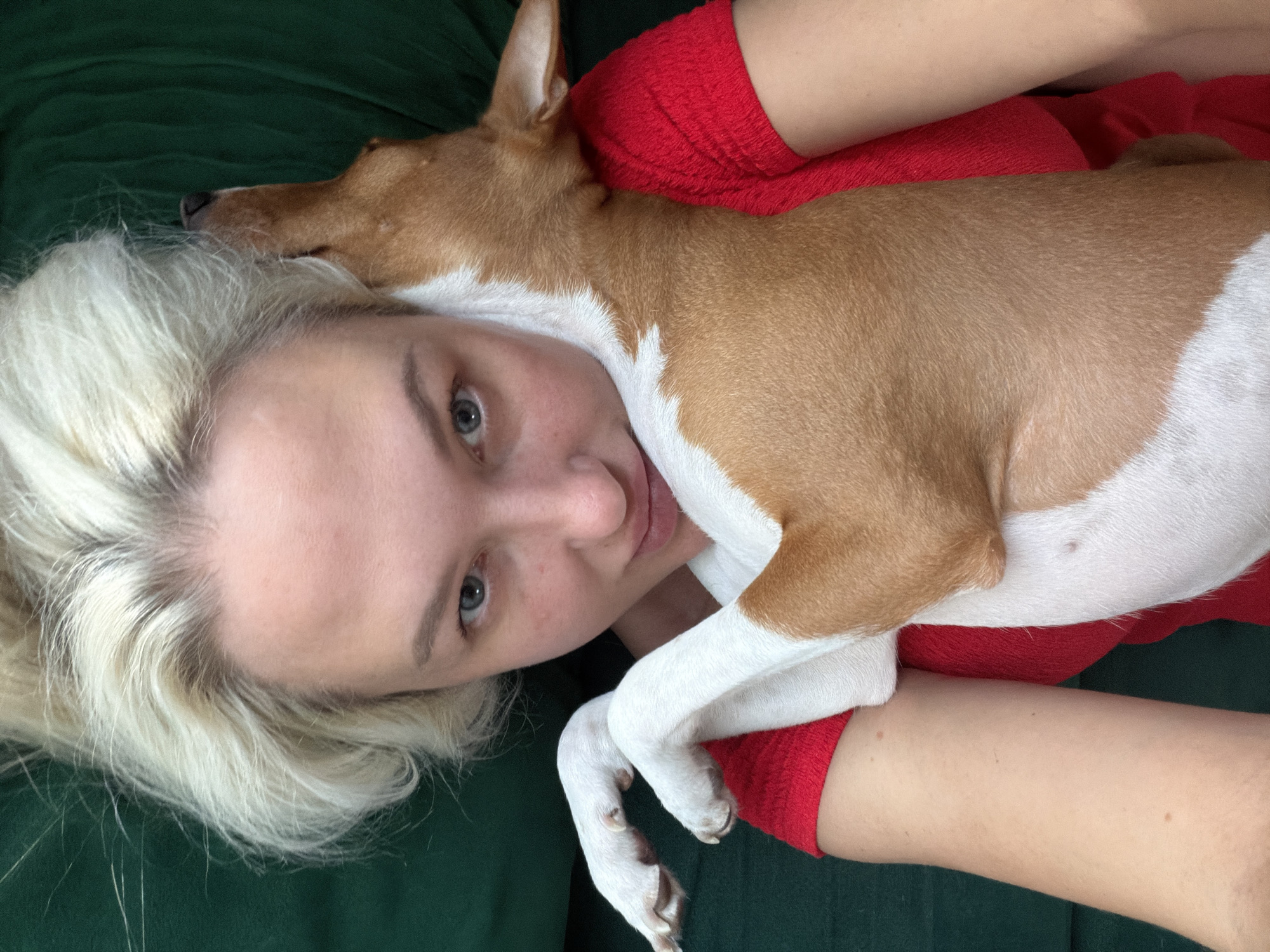 Woman and dog rest together on green surface in Salford