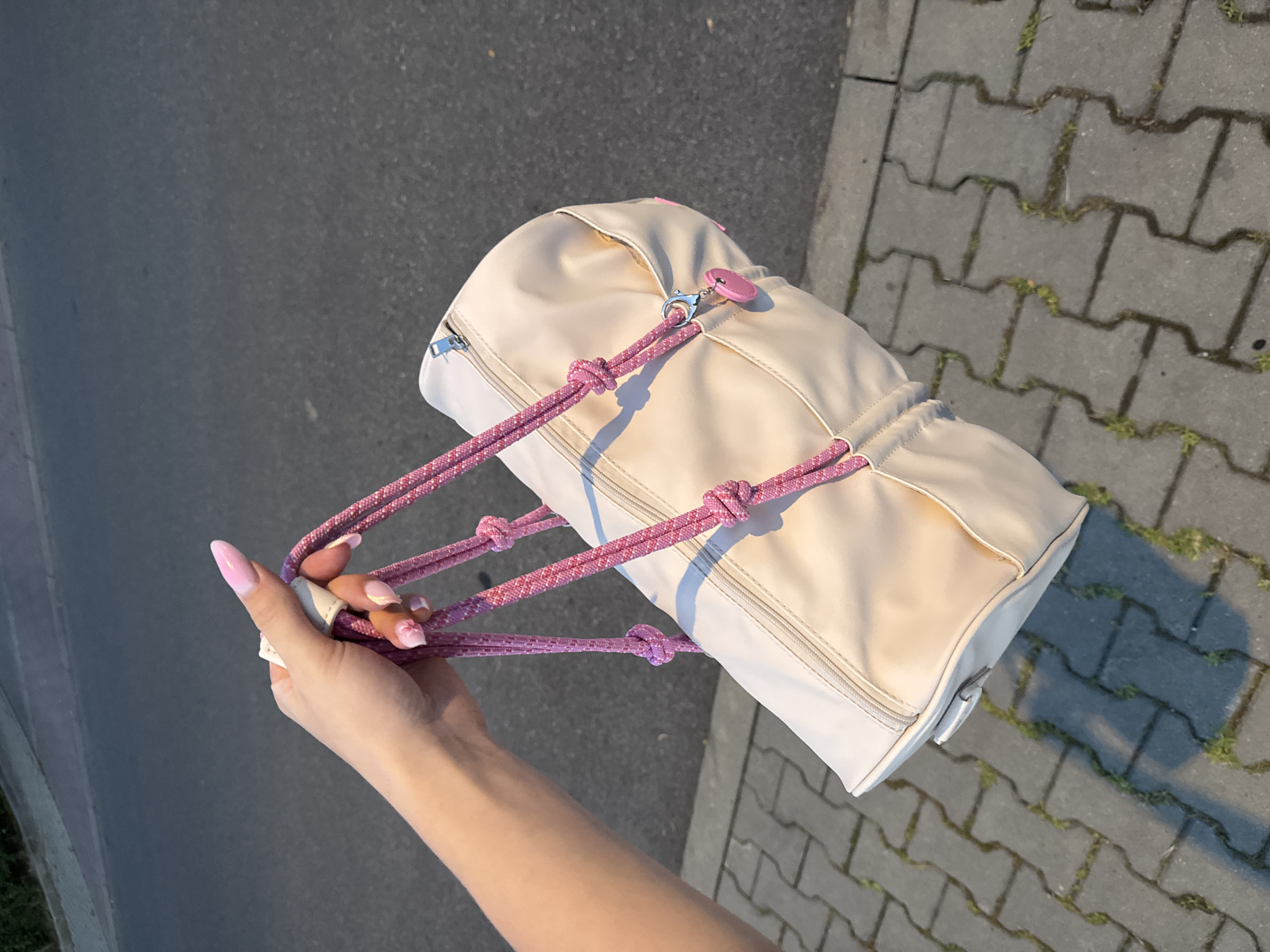 Beige cylindrical bag and black sandals on concrete pavers