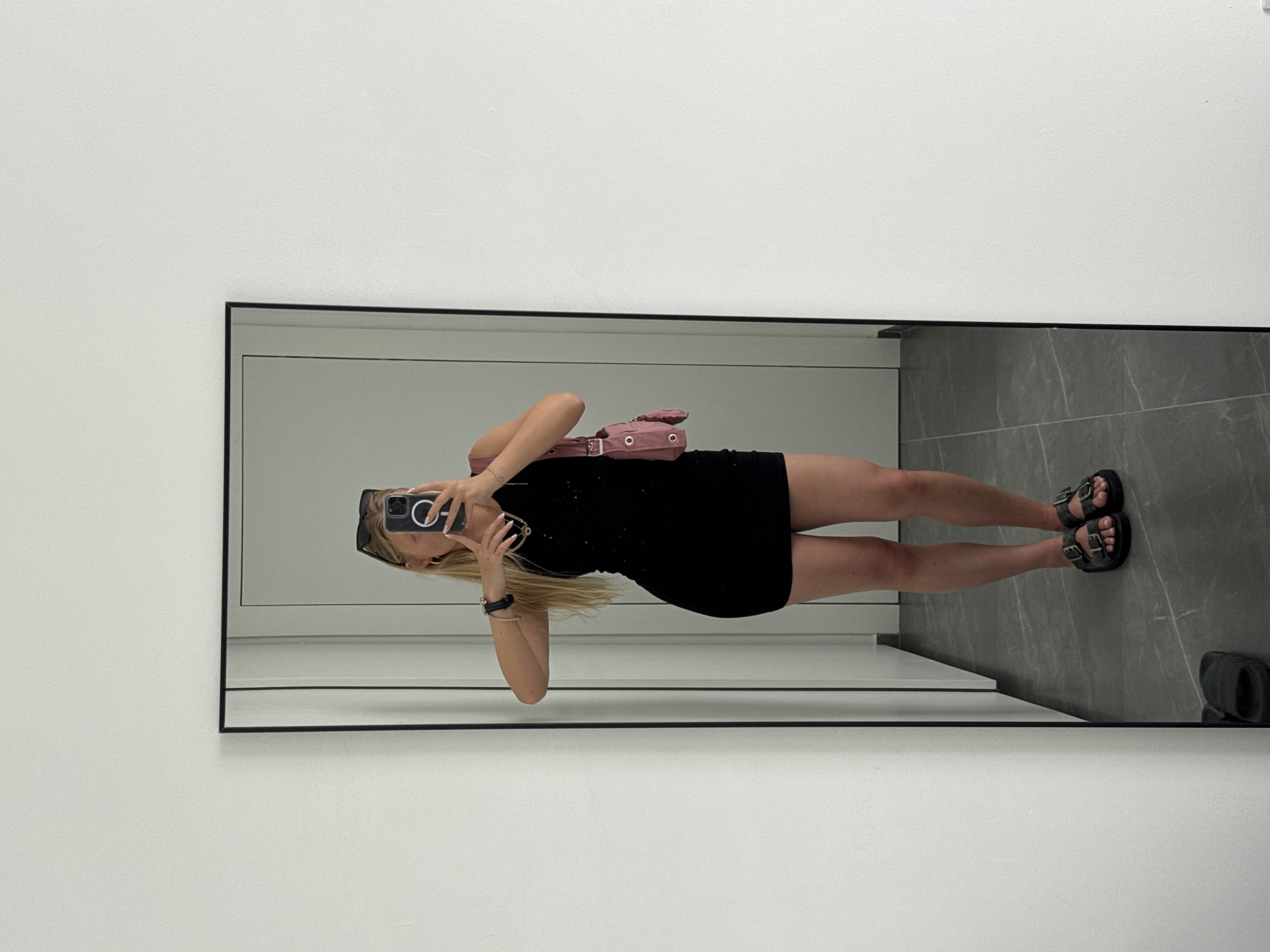 Person takes mirror selfie in black dress, Ariel