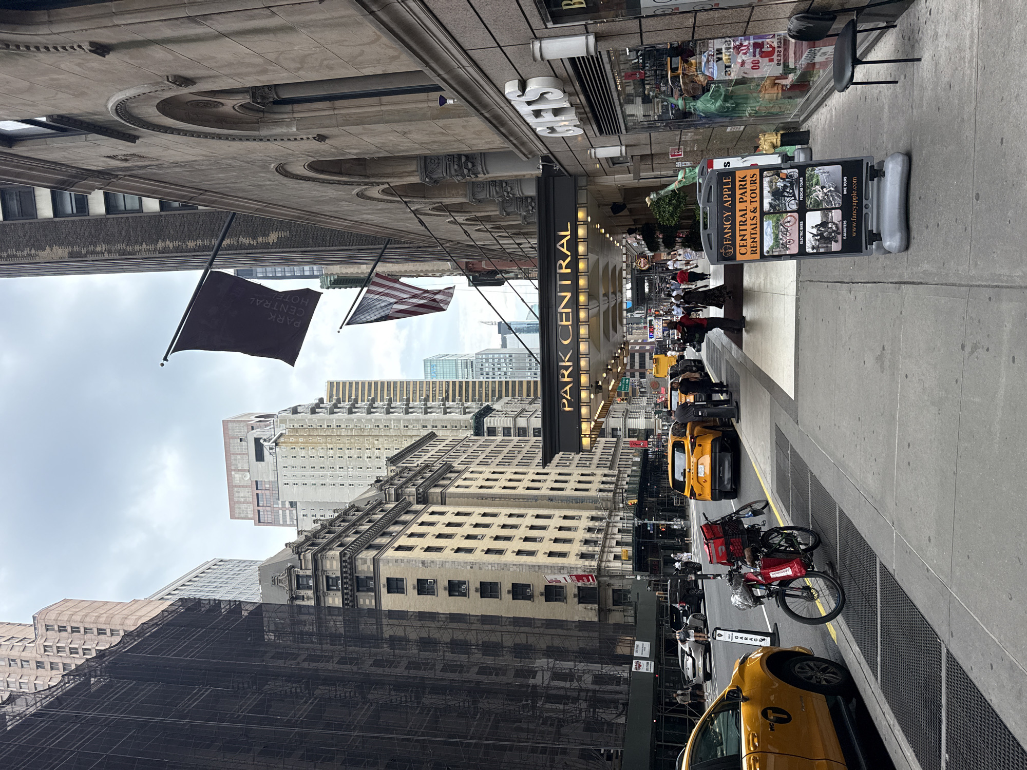 Midtown sidewalk: cabs, tourists traps, and a mini Lady Liberty