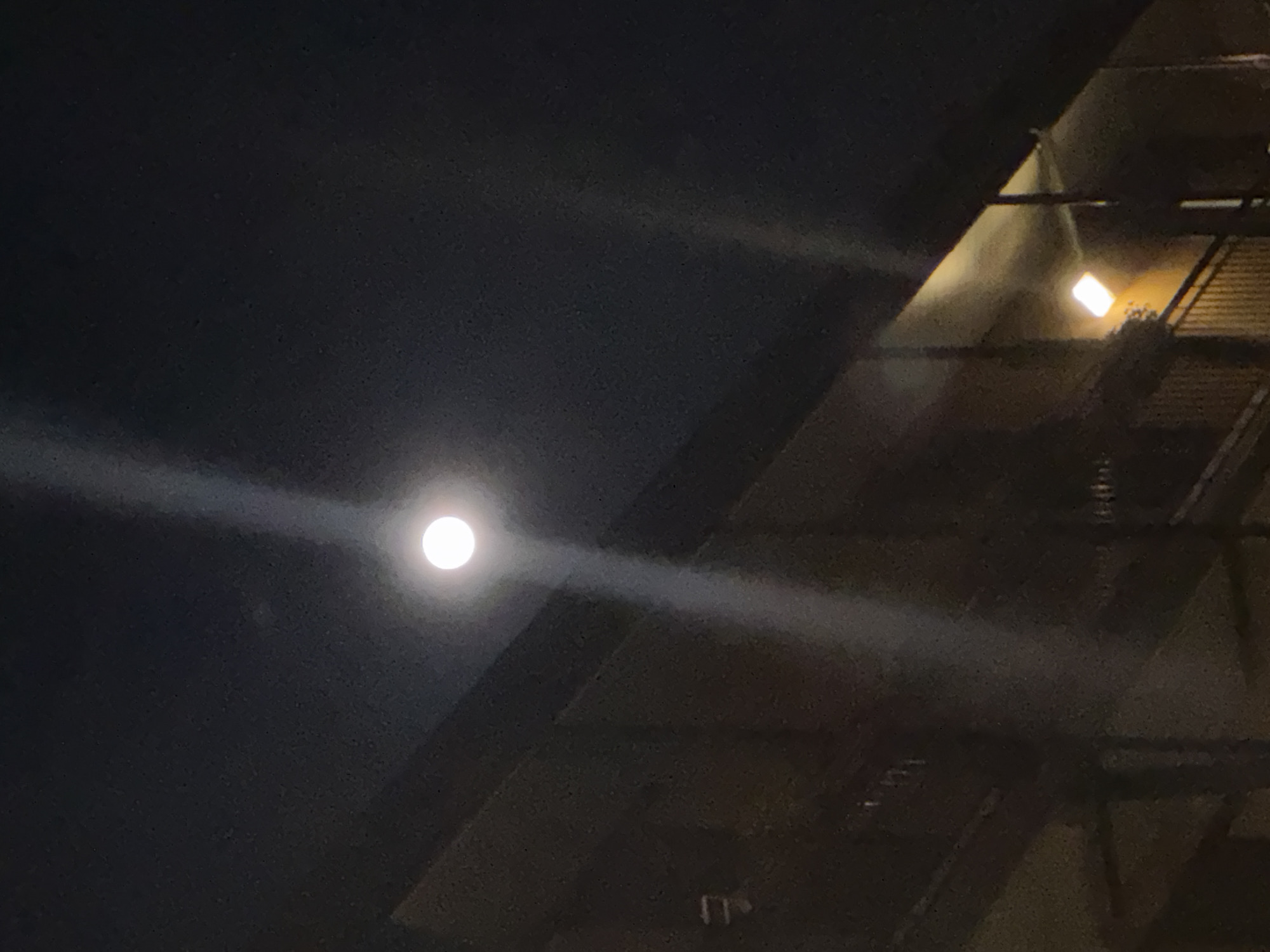 Bright moon illuminates Milan skyline with striking light-ray effect