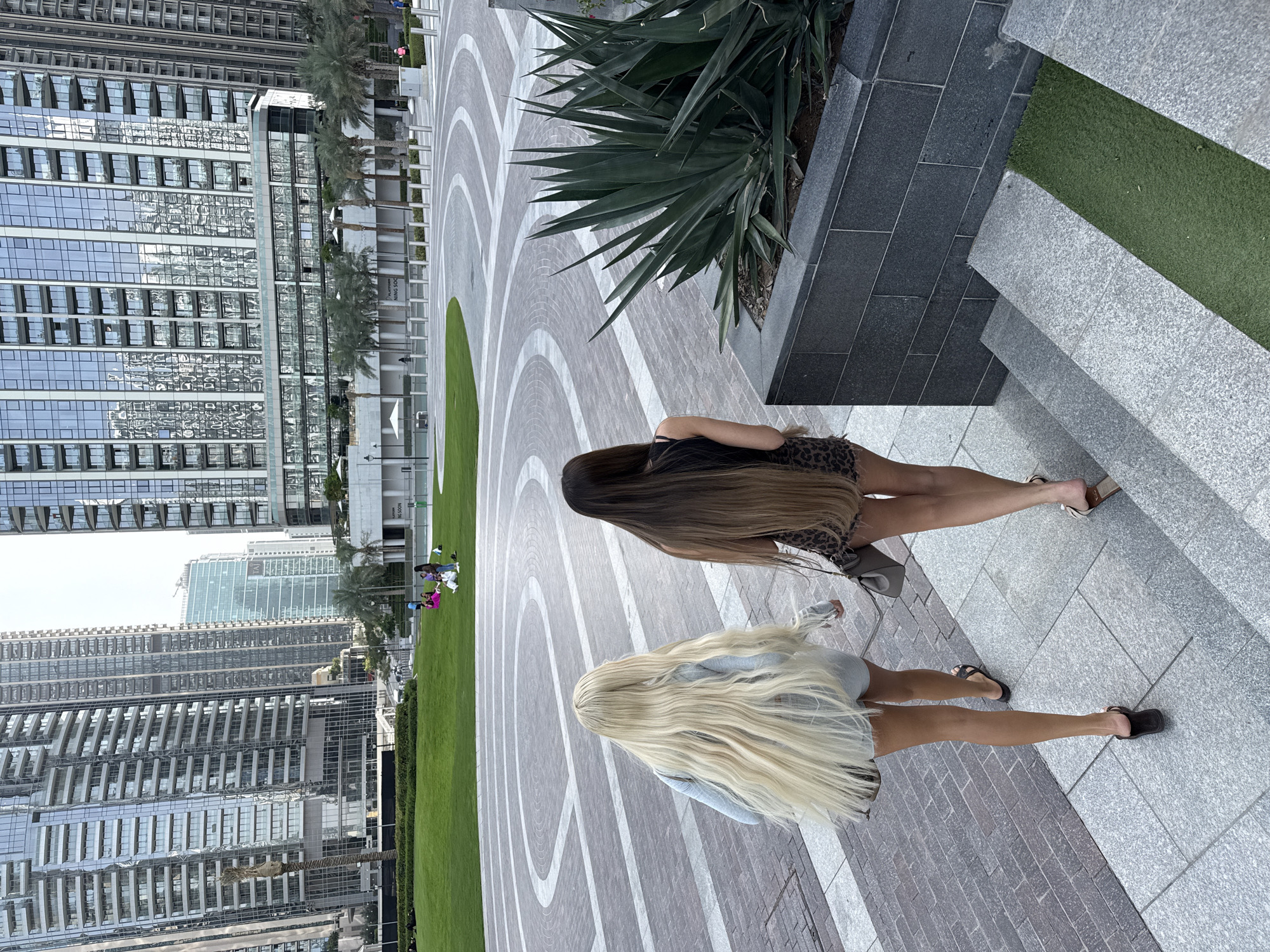 Women walk near Dubai pool with skyline views