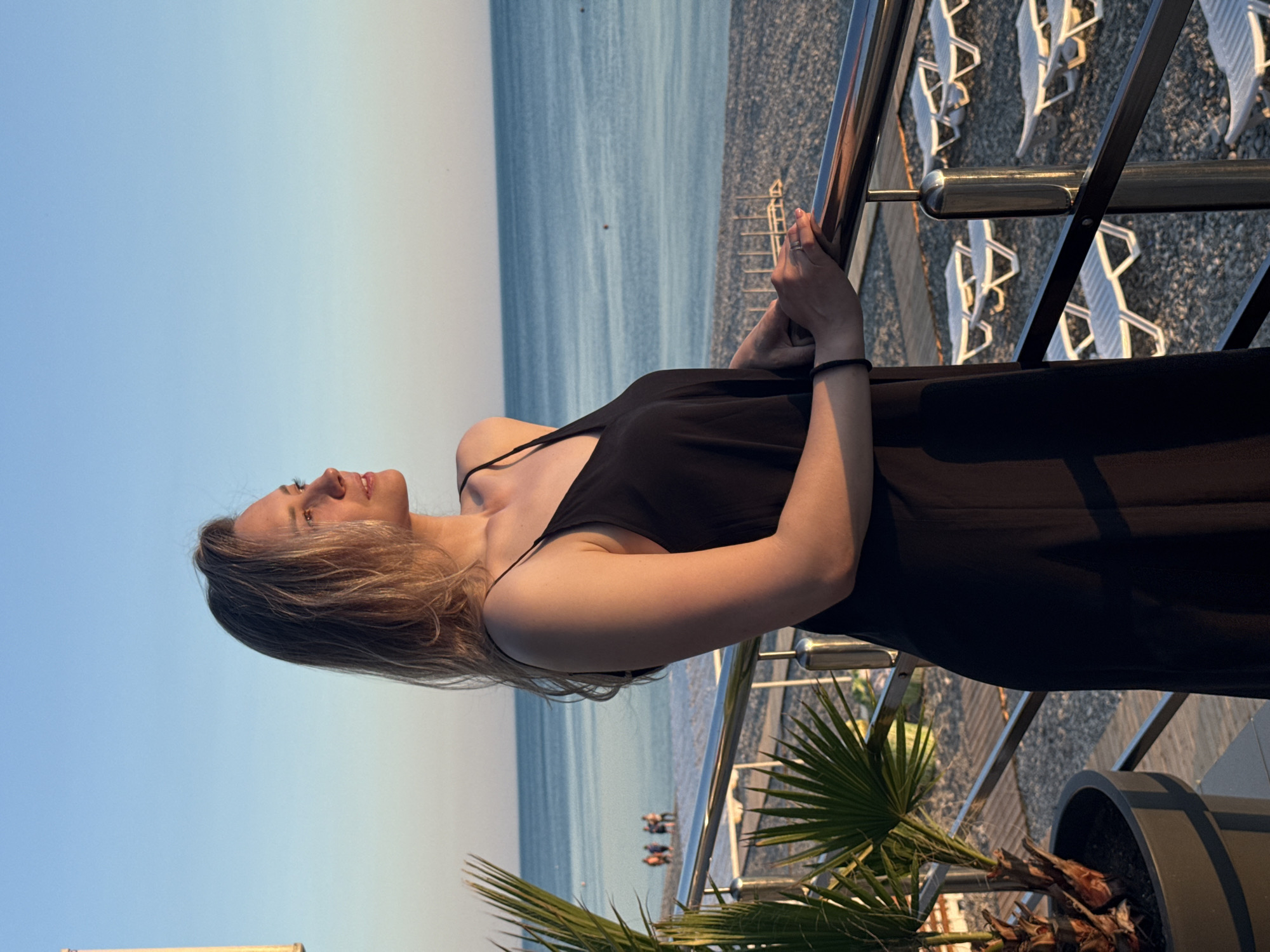 Woman enjoys golden hour moment on Nebug beach balcony
