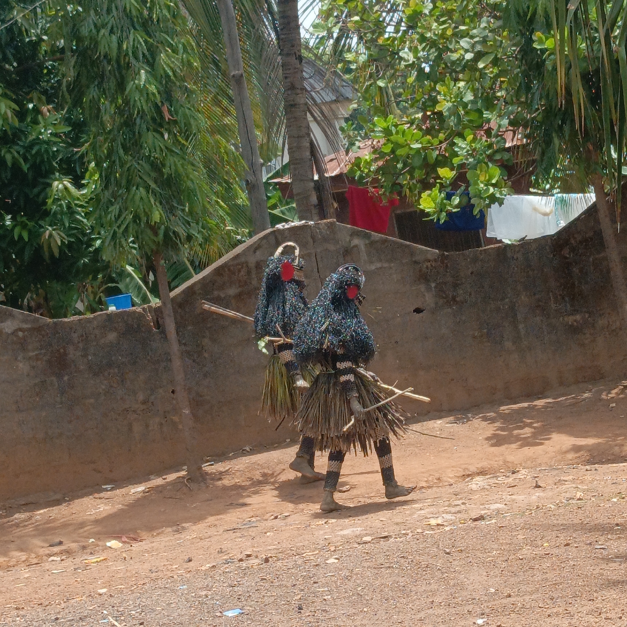 Traditional masqueraders walk through Akwanga as daily life continues