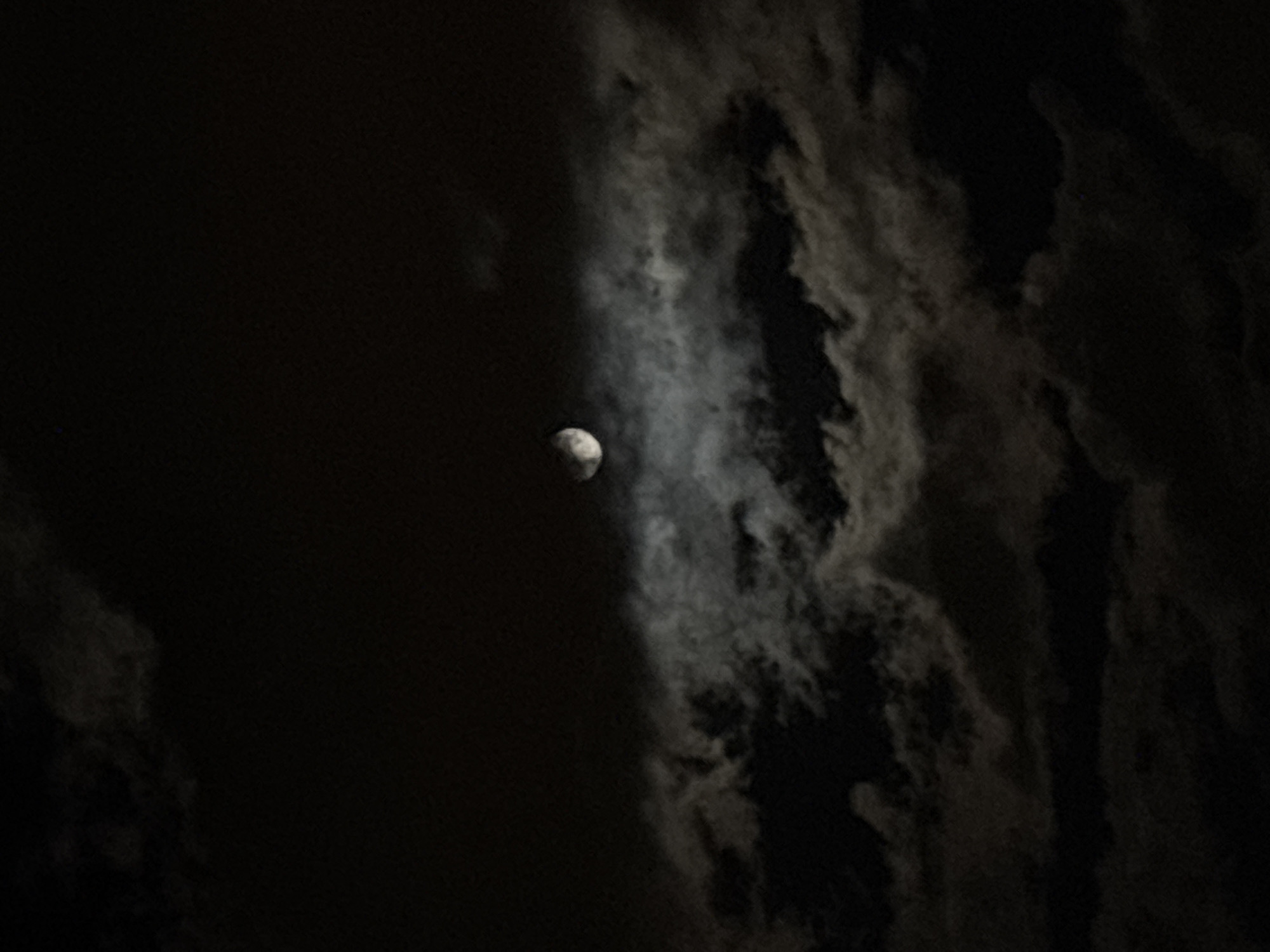 Cloudy moon photographed over Minsk evening sky