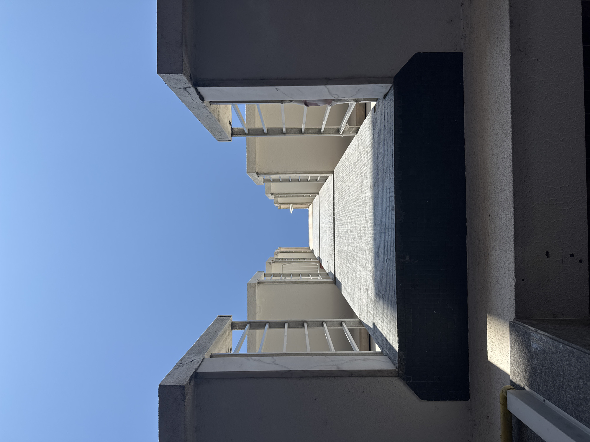Looking up between two beige apartment blocks in Oeiras
