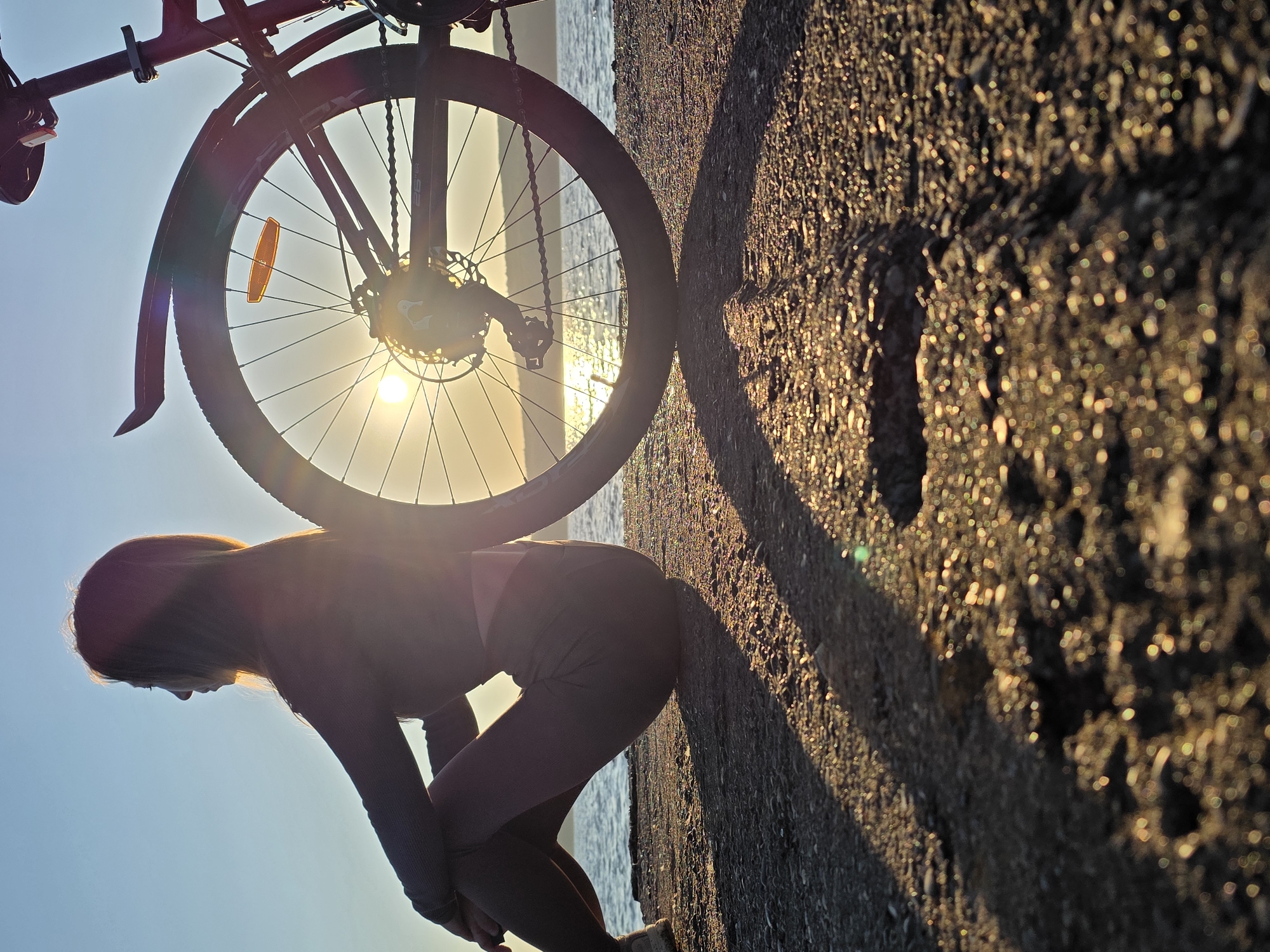 Woman with bicycle enjoys sunset by Kama River in Chaikovsky