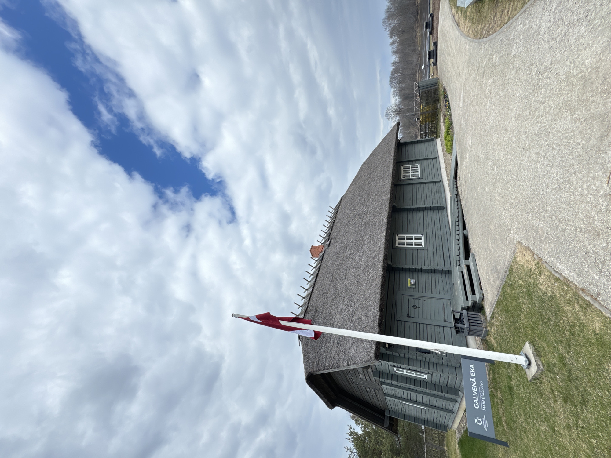 Traditional thatched building with Latvian flag observed in Carnikava