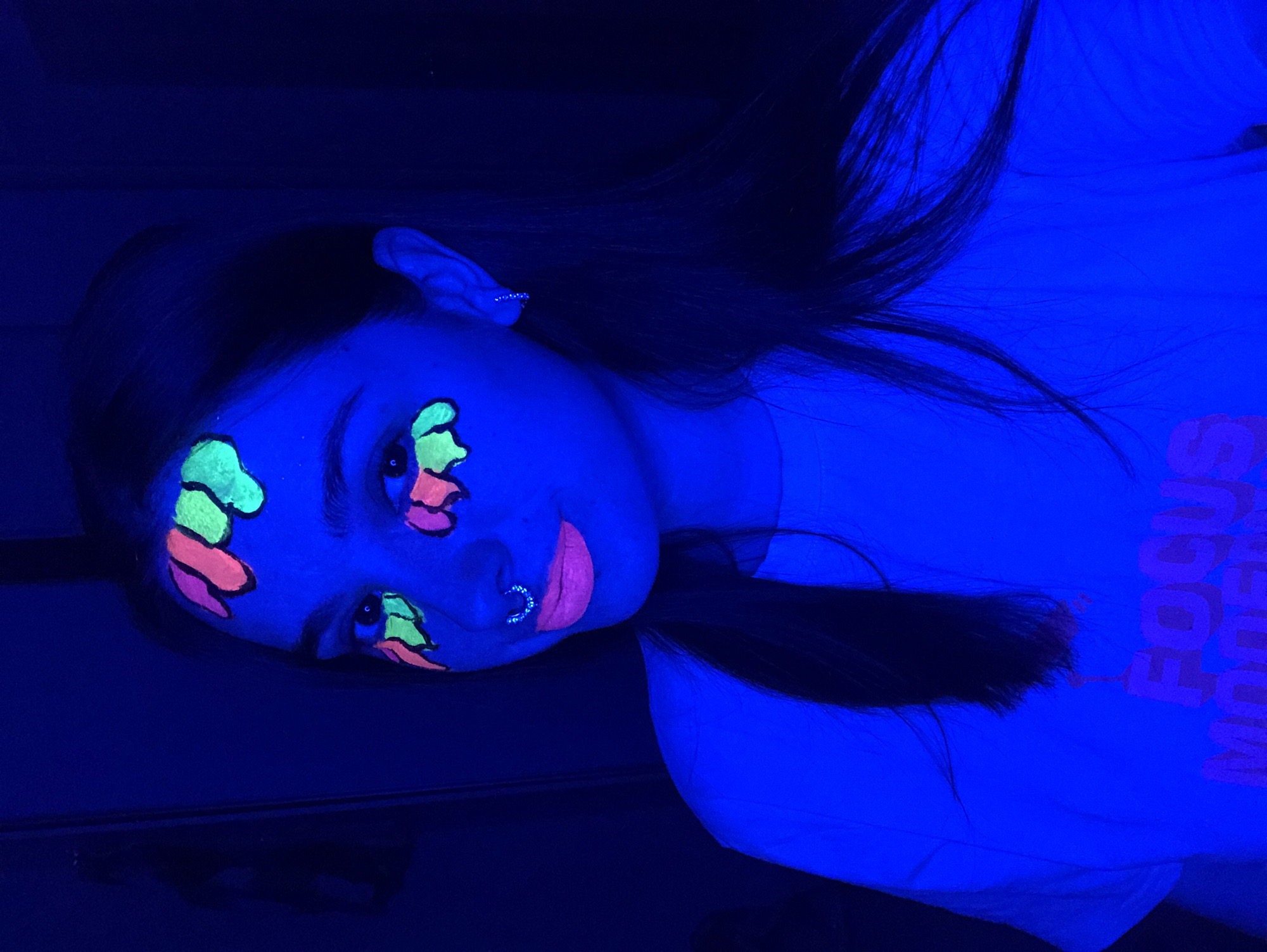 Woman documents blacklight face painting session in Noviy, Russia