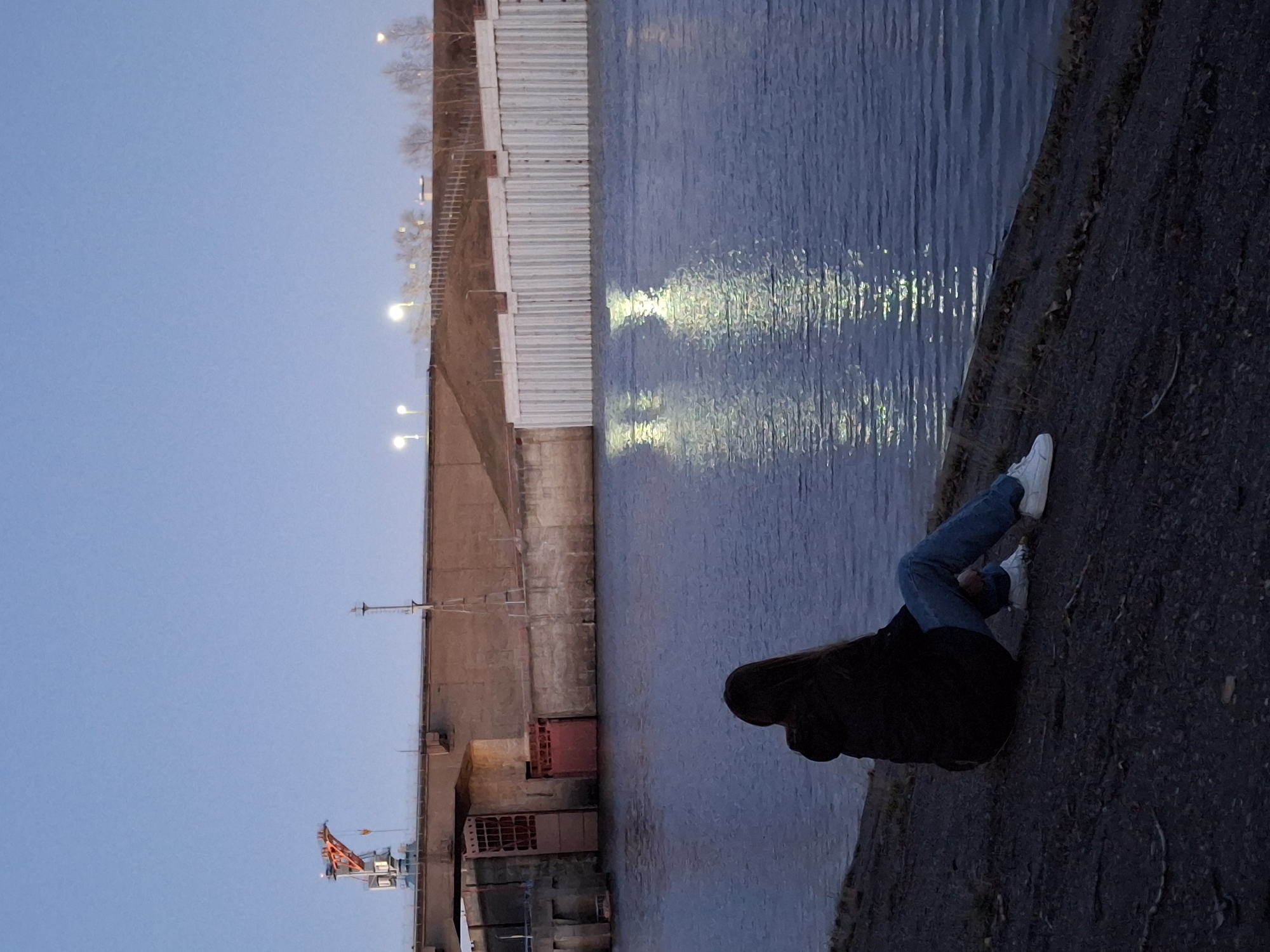 Woman sits by Kama River during sunset in Chaikovsky