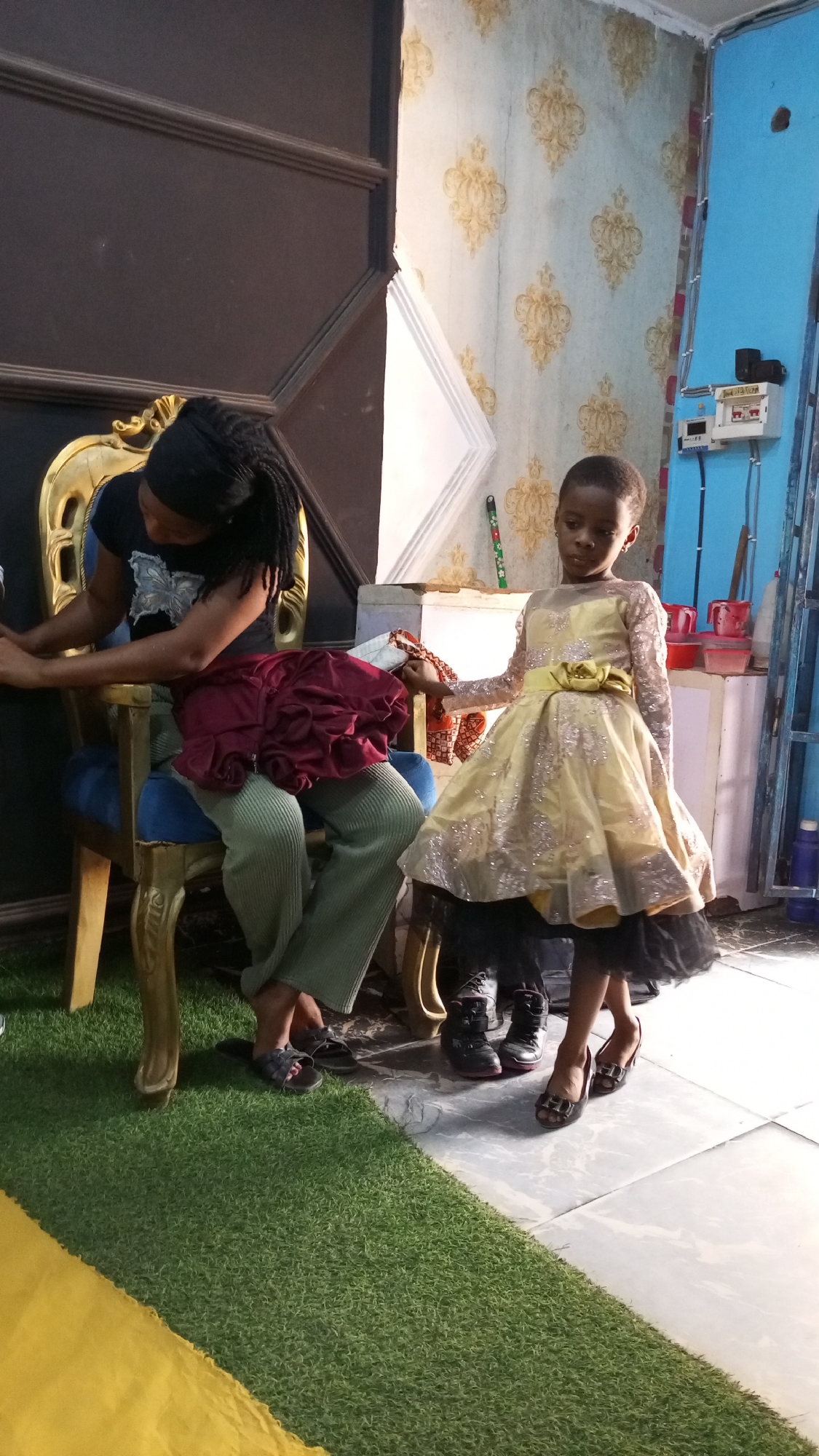 Woman helps dress children in Sabon Tasha home setting