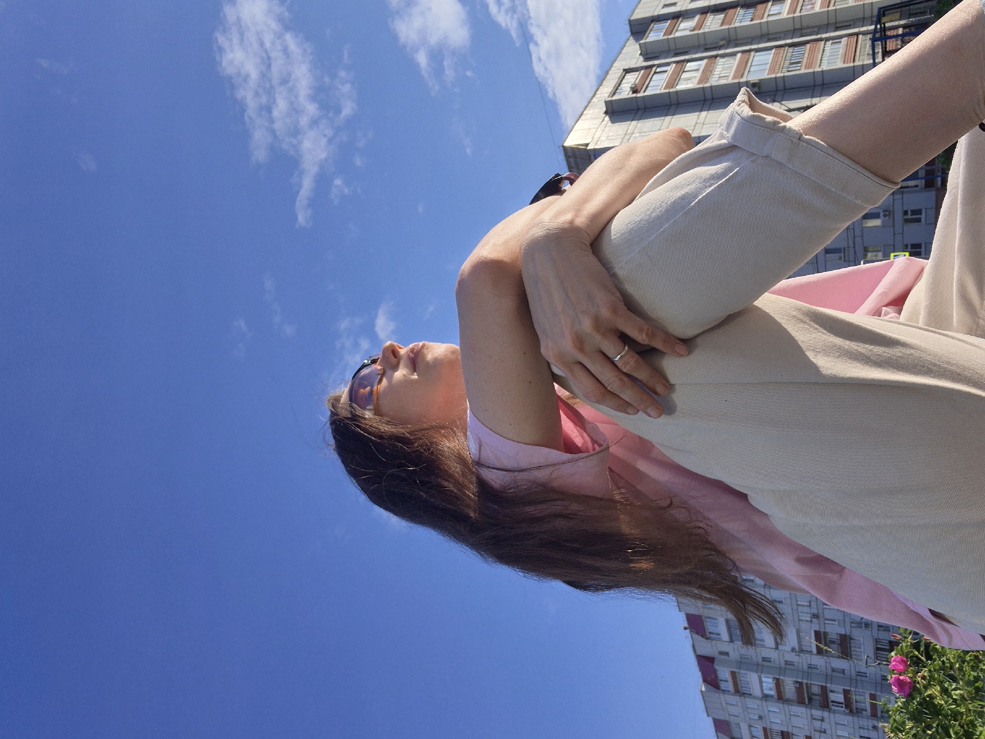 Woman in pink shirt sits outdoors in casual afternoon moment