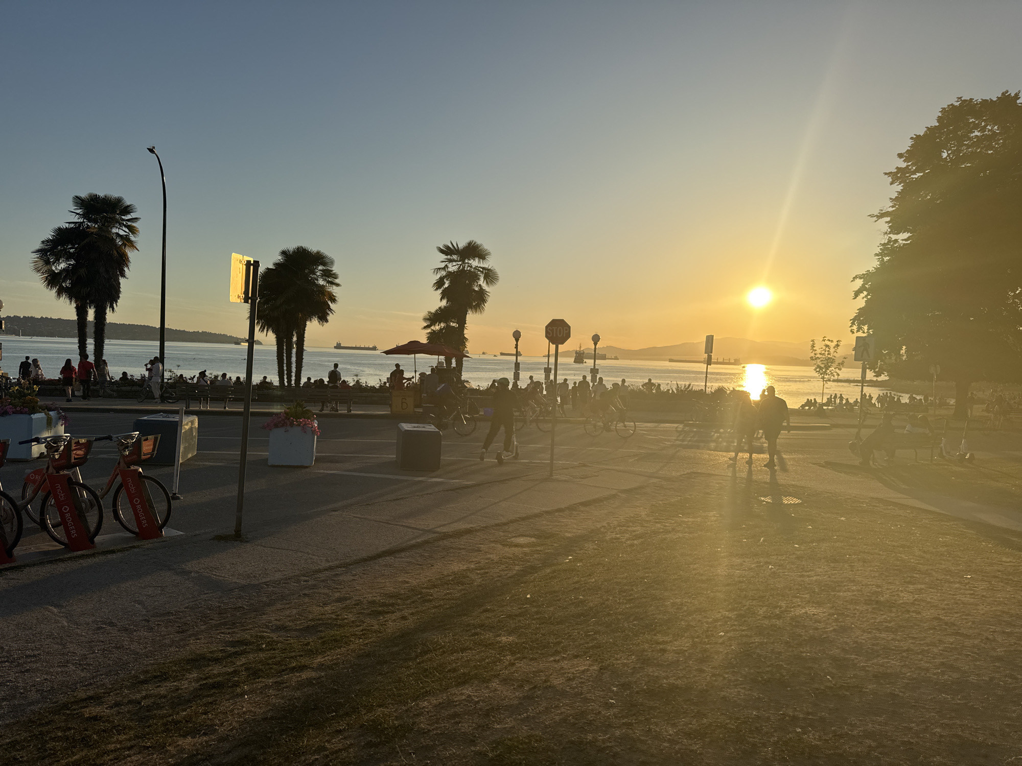 Yue Minjun's laughing bronze figures at English Bay, golden hour