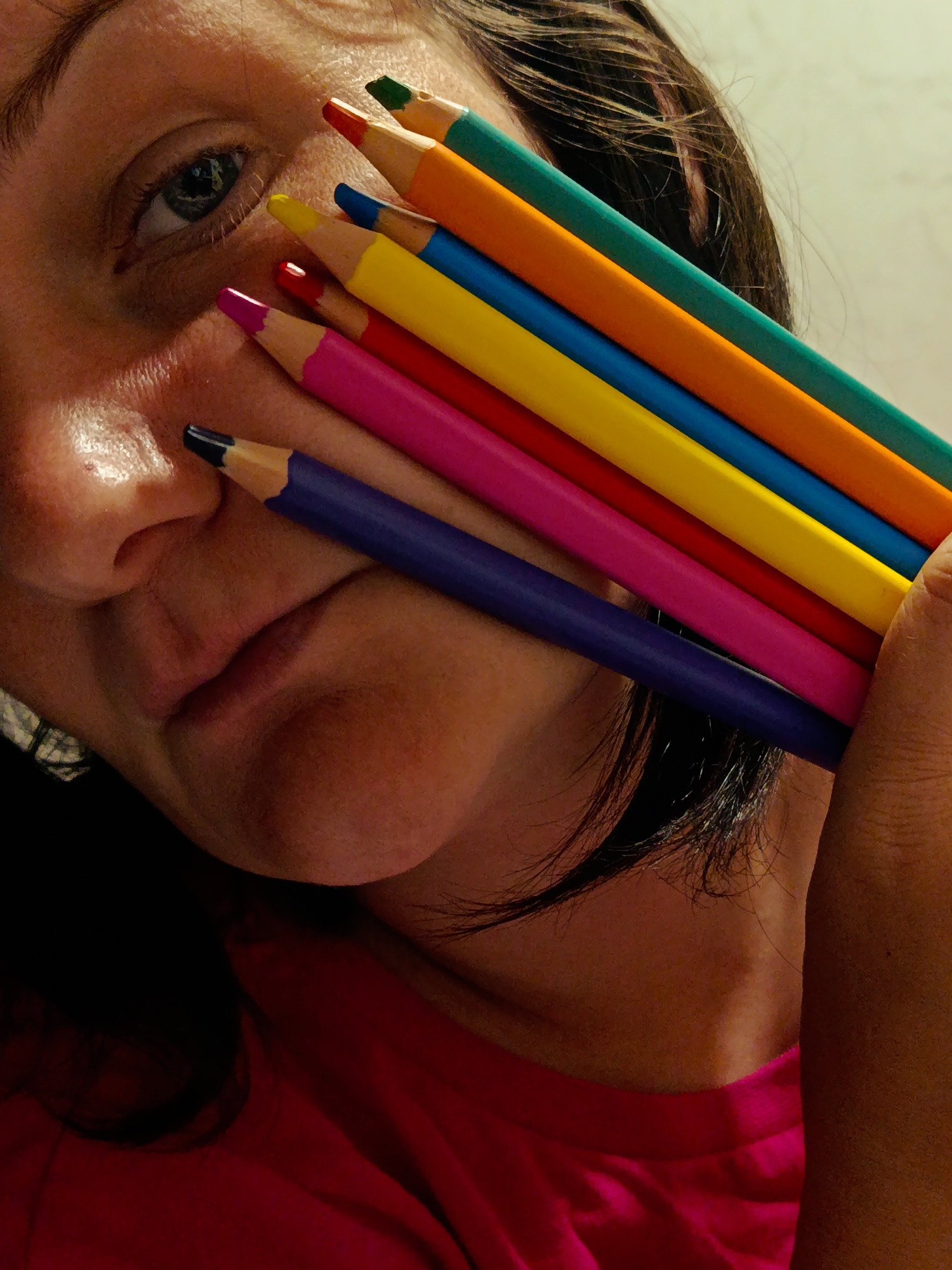 Person poses with colored pencils in indoor portrait