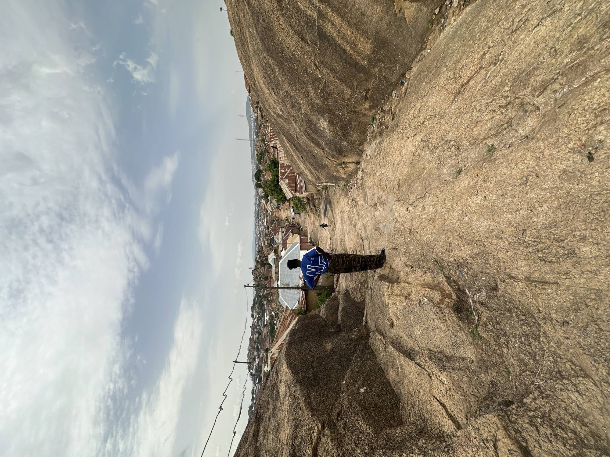 Person in camouflage overlooks Jos from rocky cliff