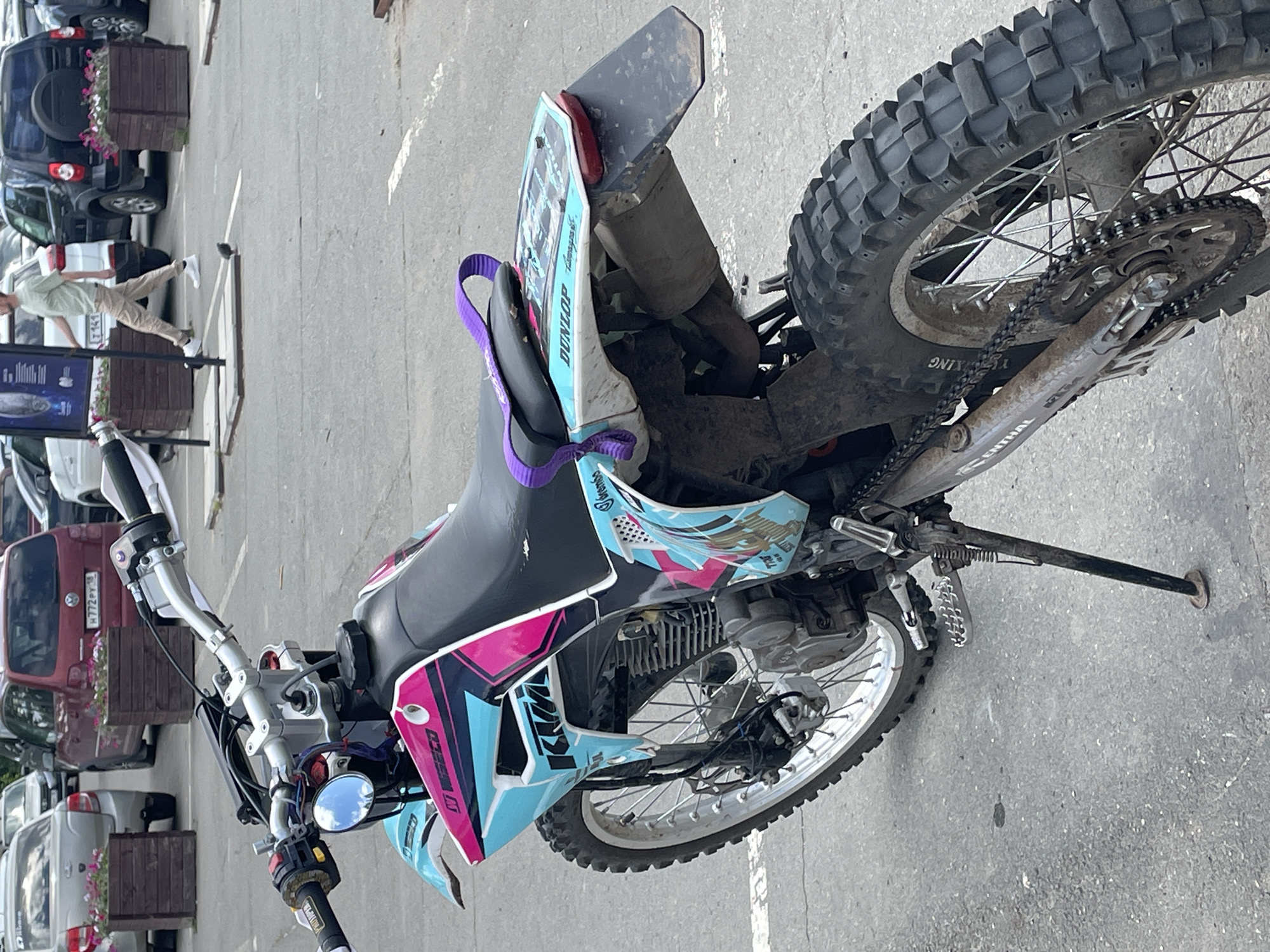 Urban scene captures parked dirt bike, white statues against blue sky