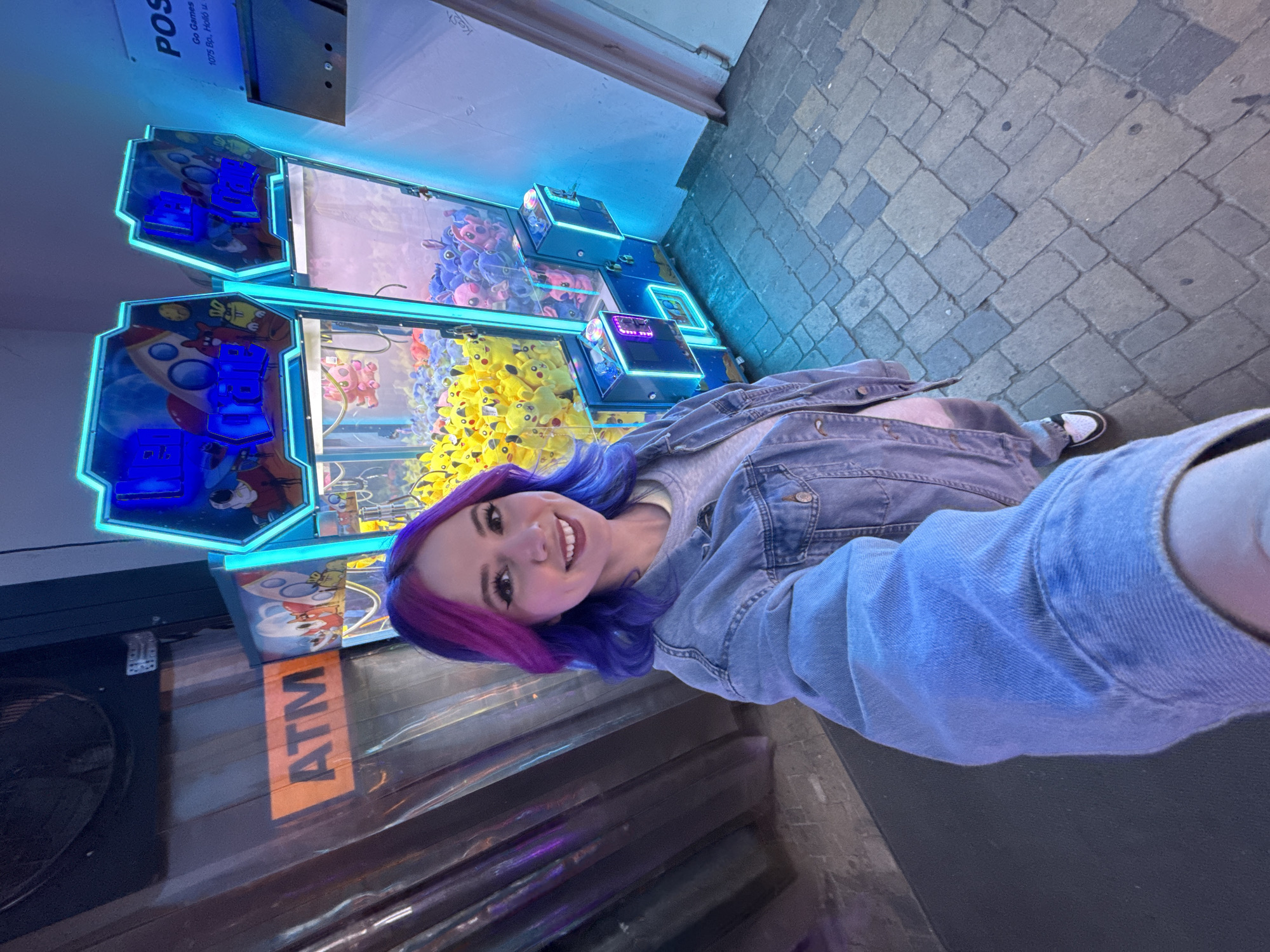 Woman takes selfie at Pikachu claw machine arcade Budapest