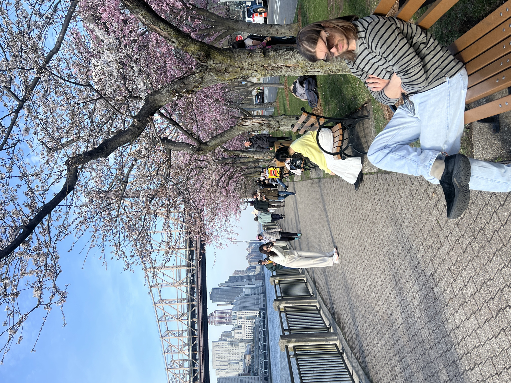 Women pose by East River during cherry blossom bloom