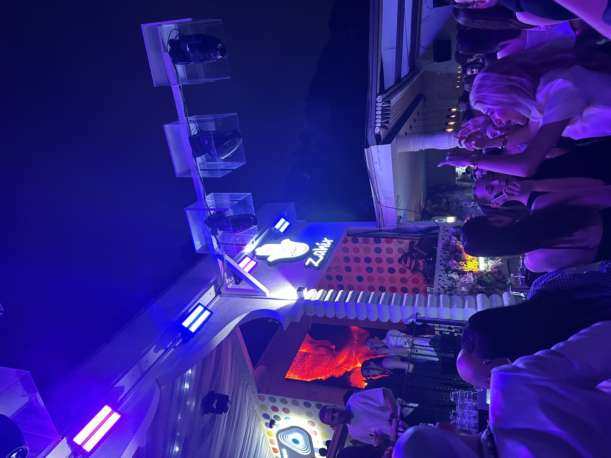 Nighttime bar gathering with dancing under colored lights documented