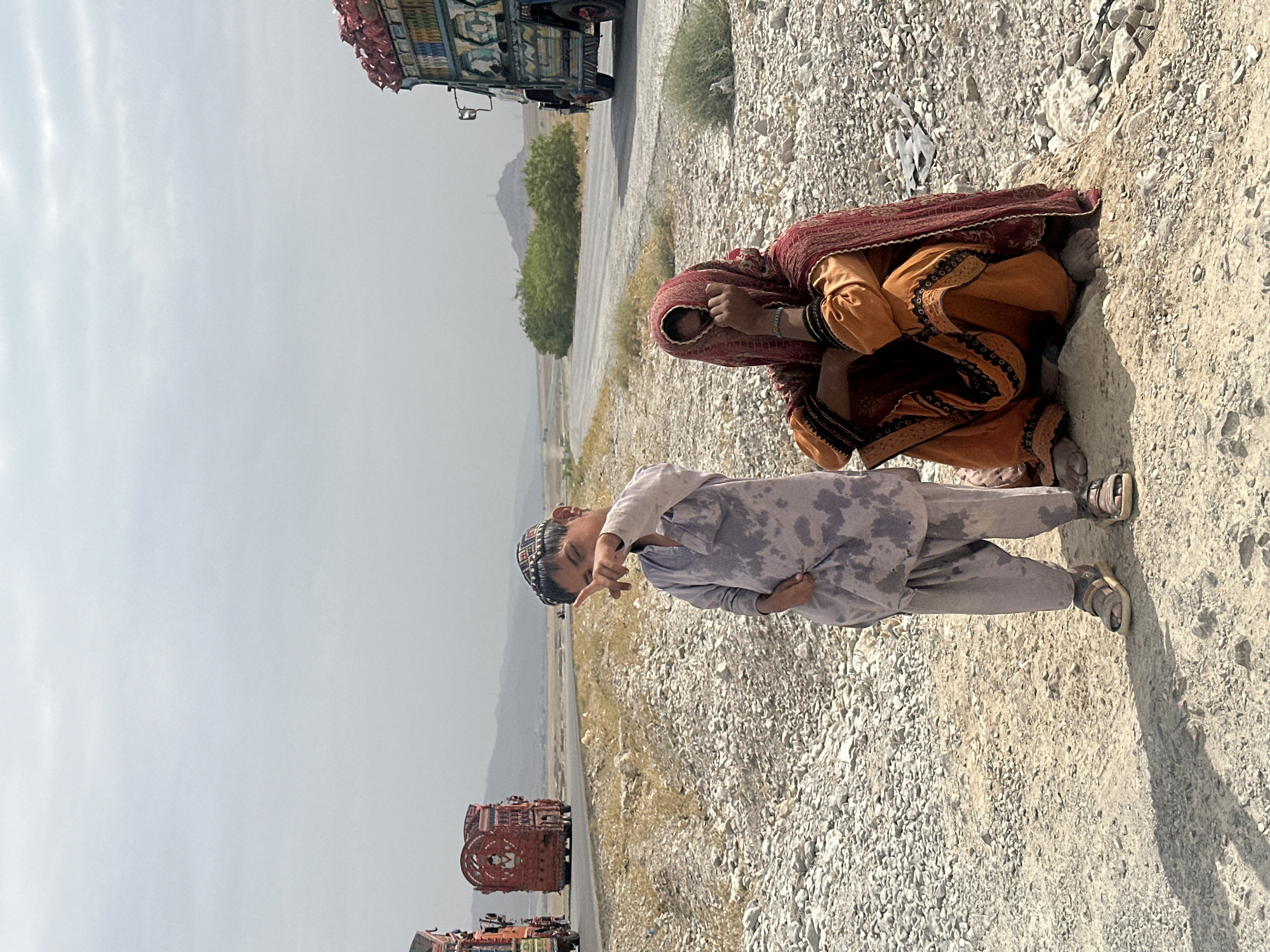 Pointing toward the distance on a rocky Khanai Baba roadside