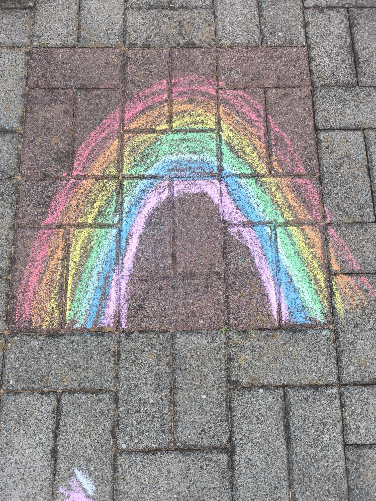 Chalk rainbow artwork spotted on outdoor paving stones