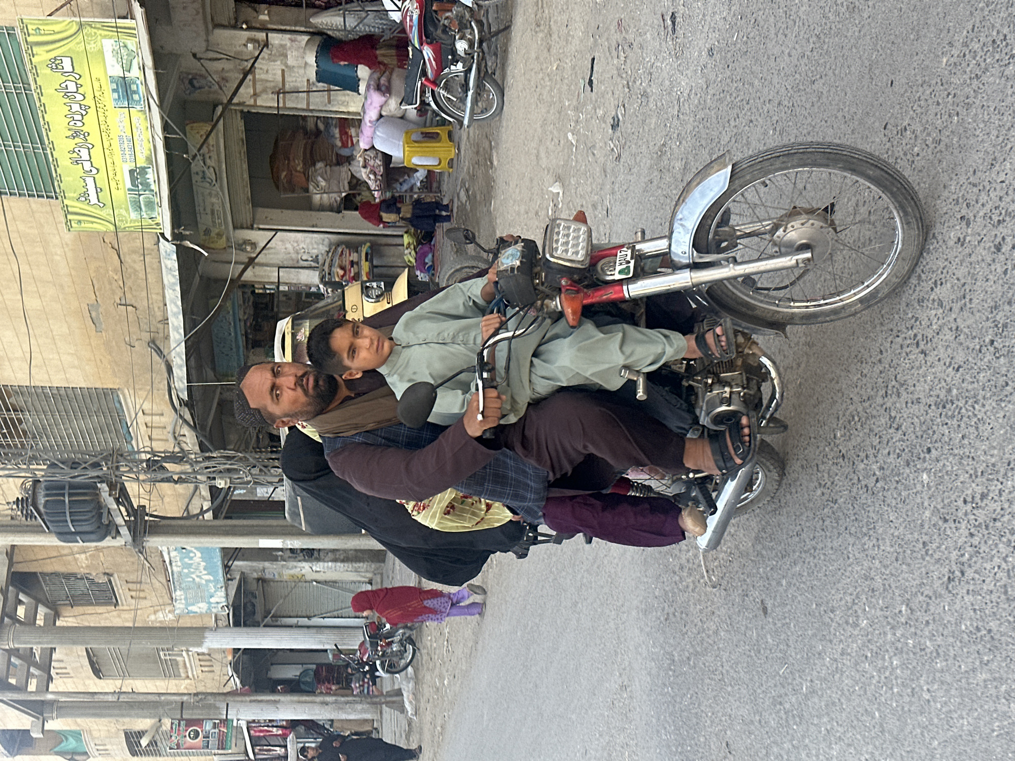 Red motorcycle moving through Quetta city streets