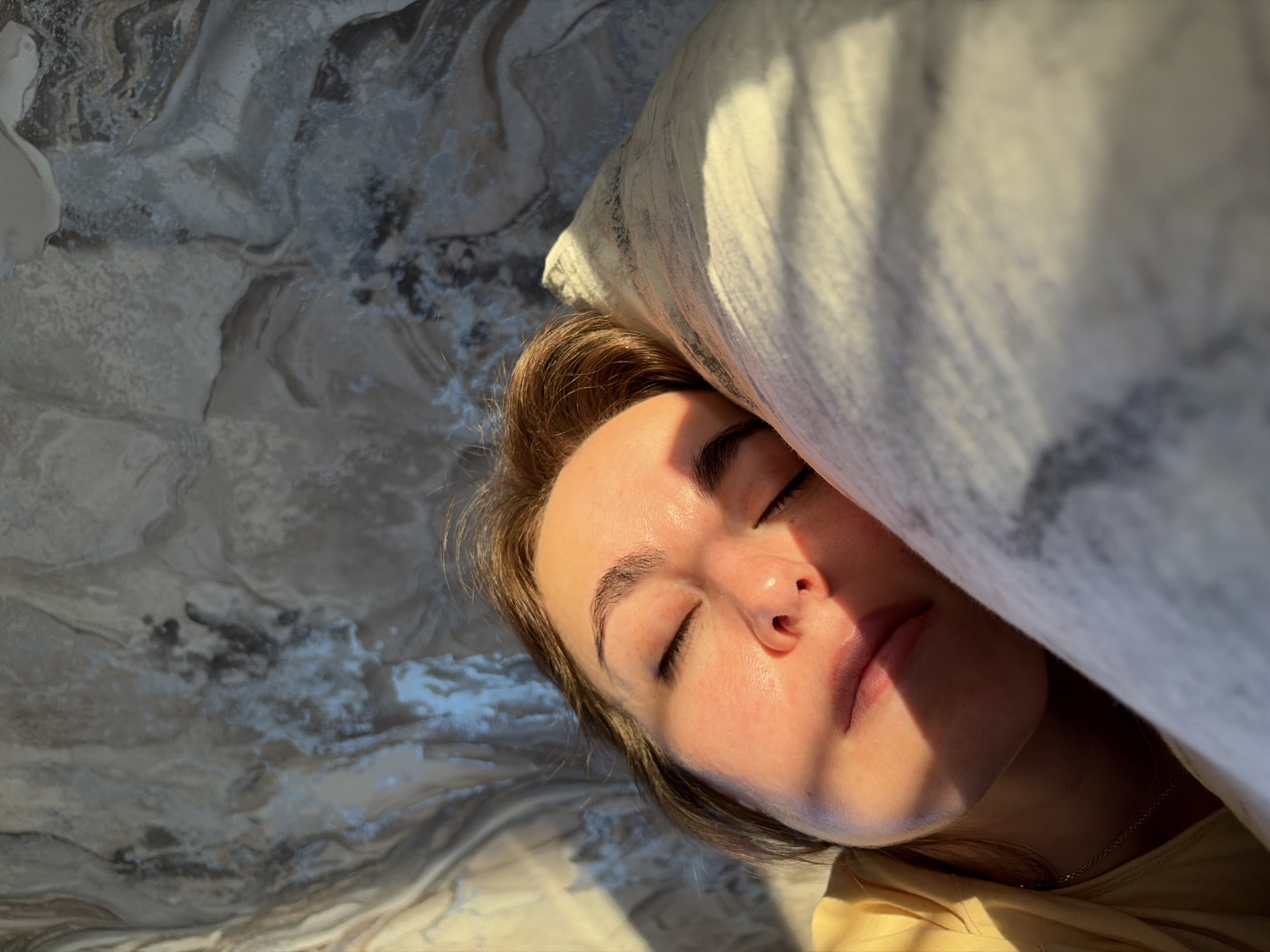 Woman rests in sunlit bedroom in Izhevsk