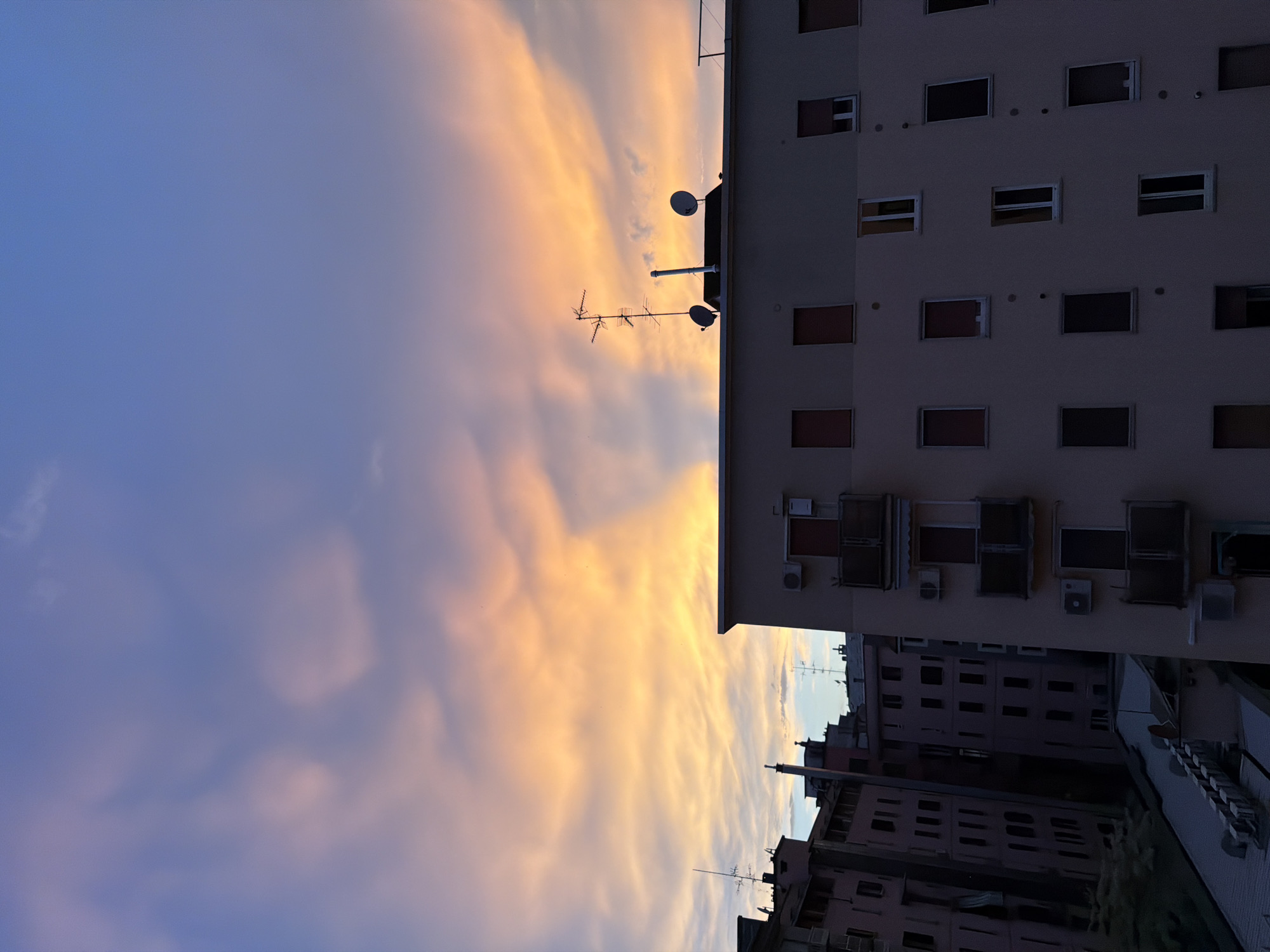 Milan's summer sunset, watched from the neighborhood rooftops and windows