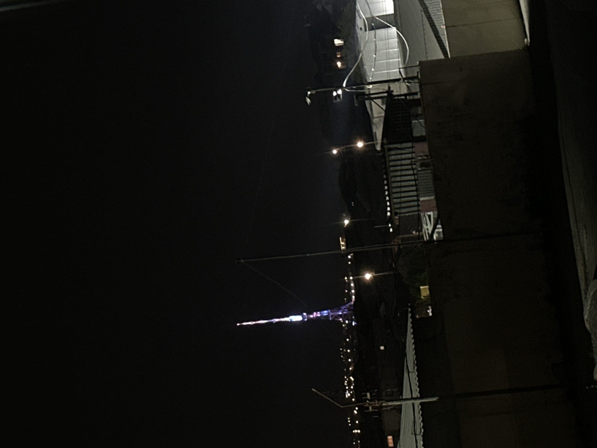 Nighttime urban documentation captures illuminated tower, vehicles, buildings