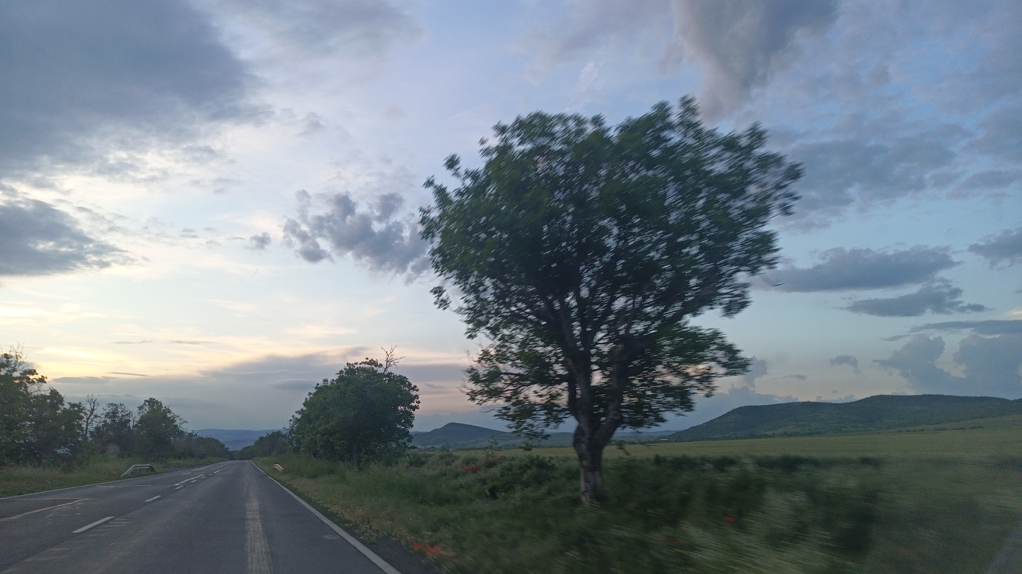 Road stretches toward horizon under cloudy skies in Bulgaria