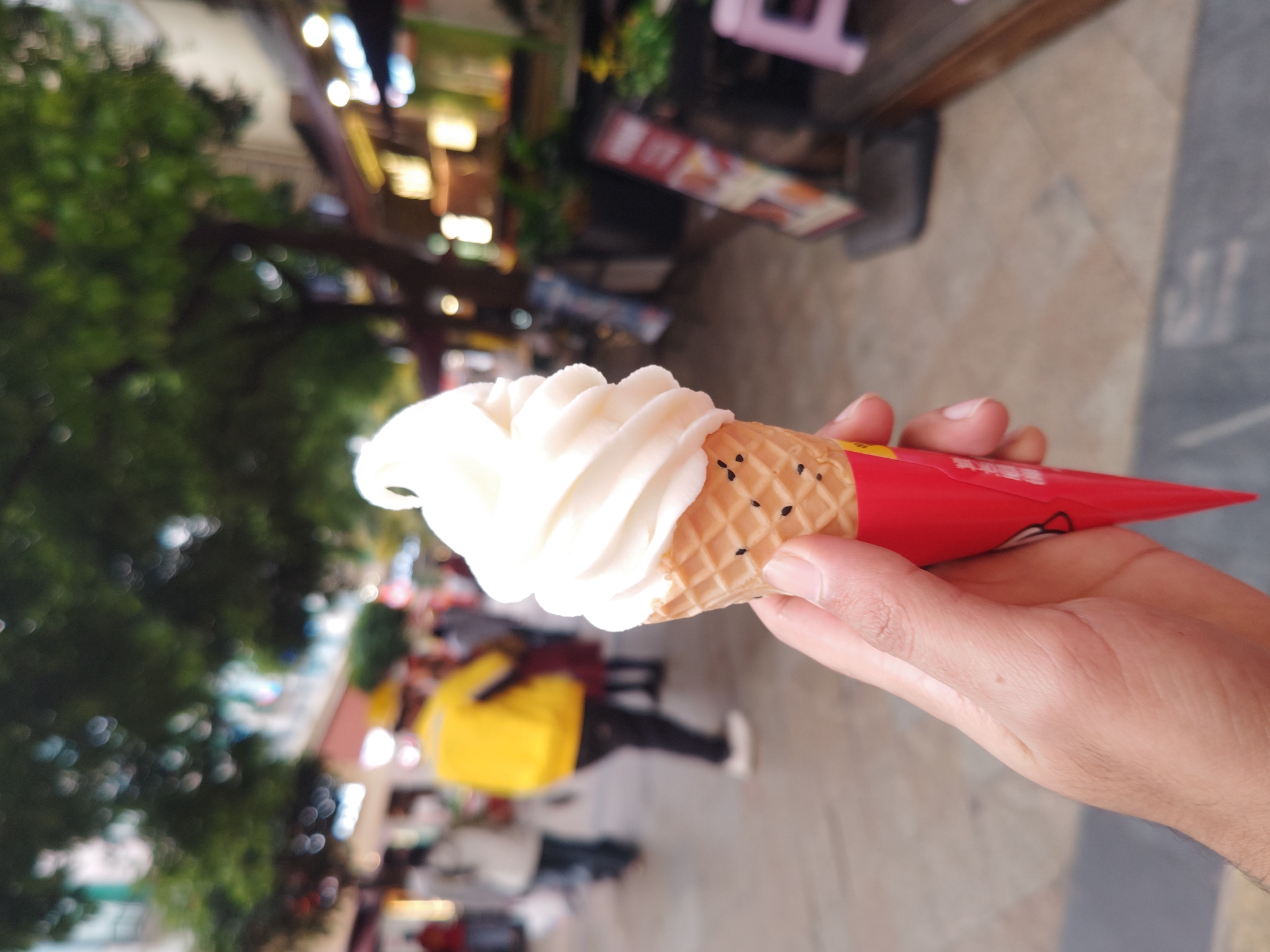 Person enjoys soft-serve ice cream on busy Chinese street