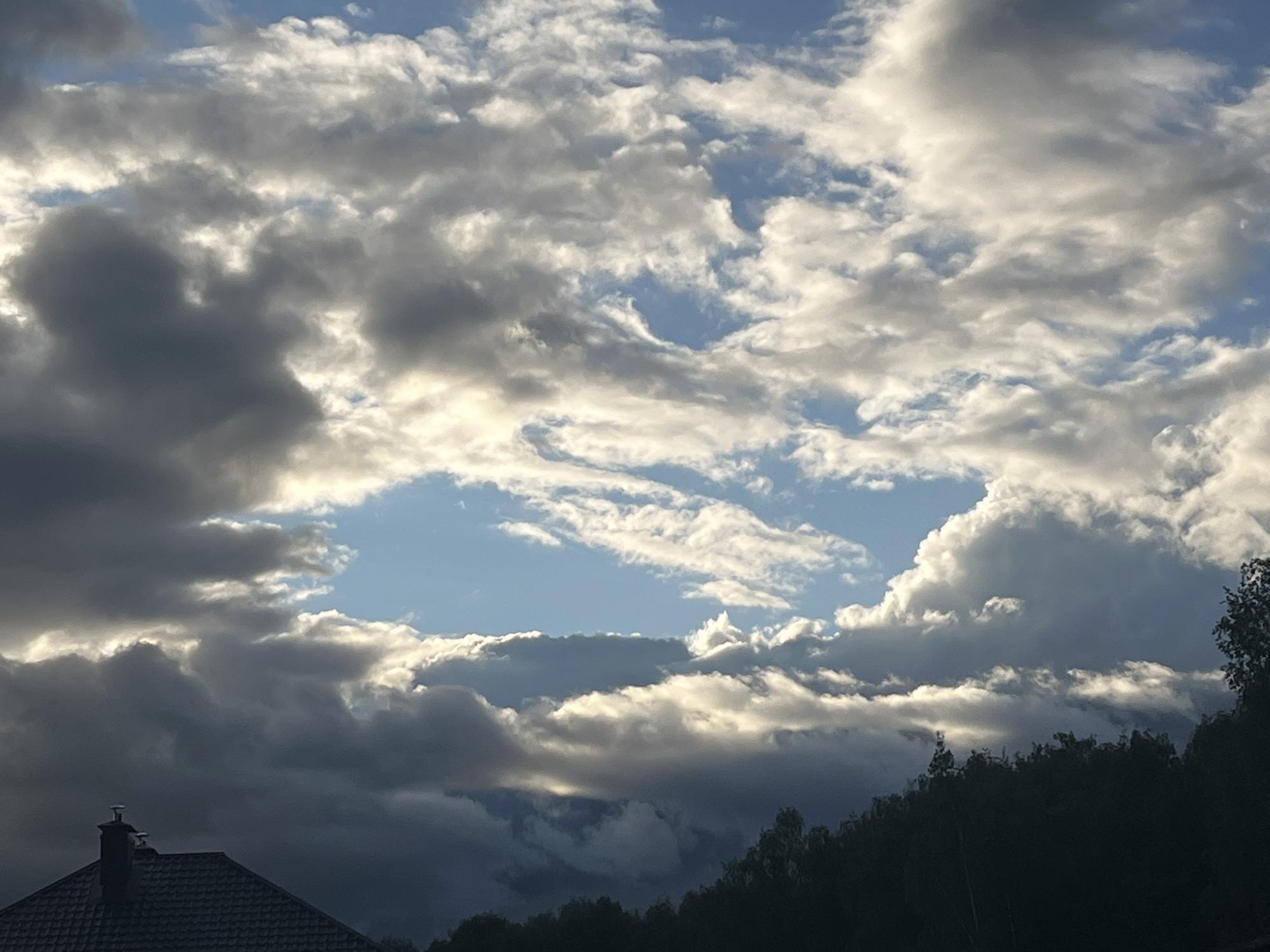 Partly cloudy skies with contrail observed over residential area