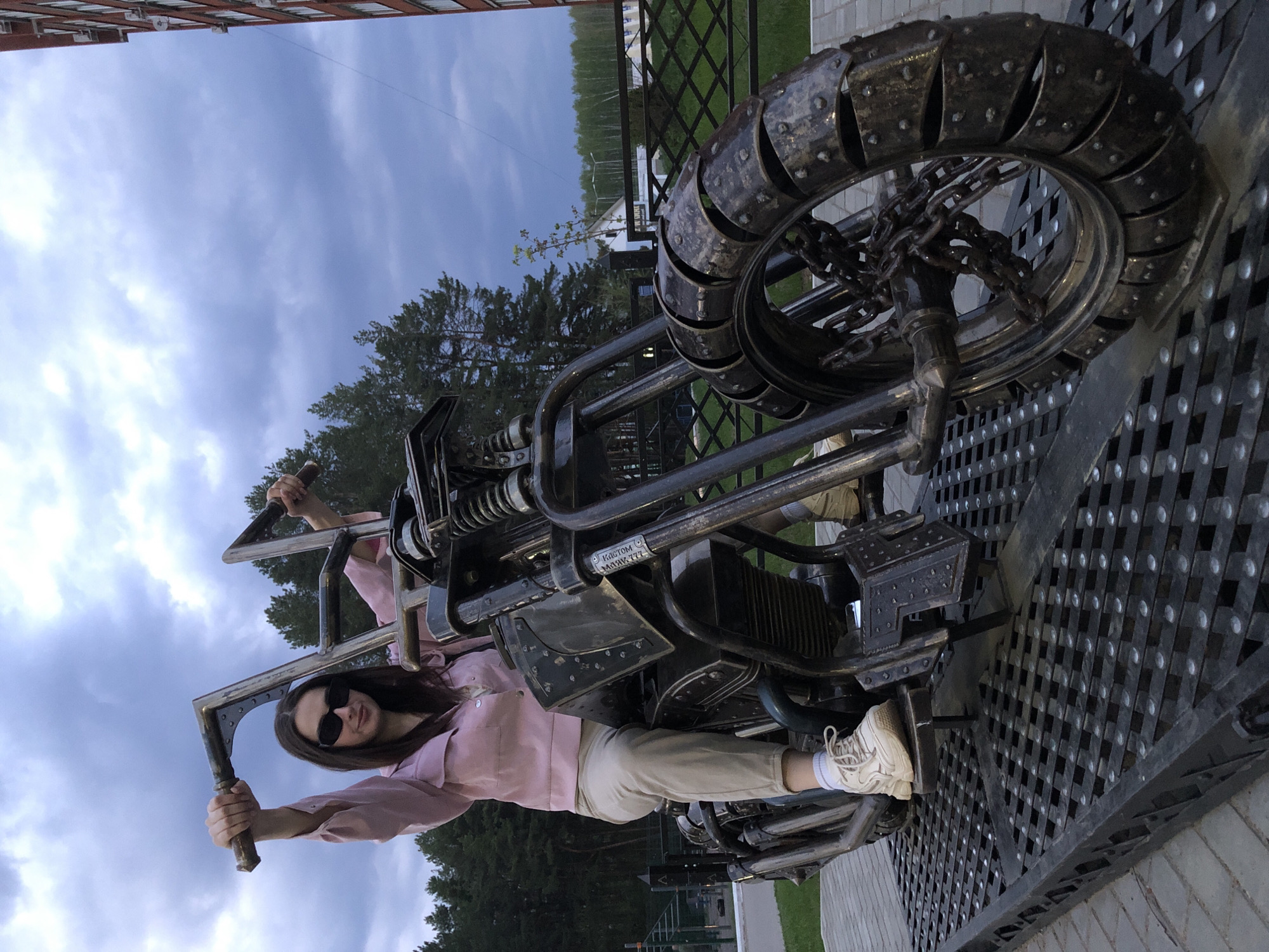Woman poses on motorcycle sculpture in Chaikovsky, Russia