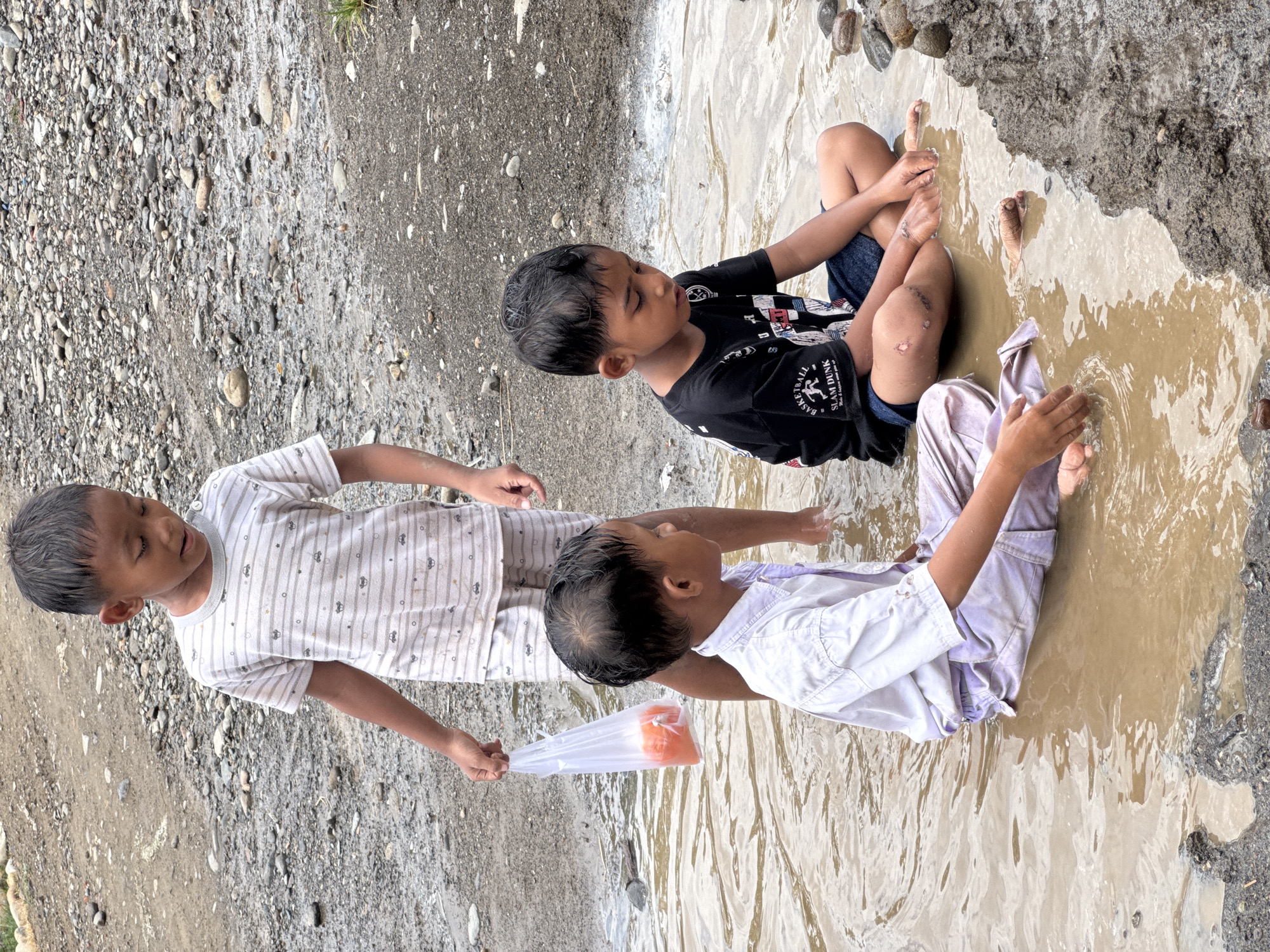 Kids in school uniforms splash through muddy puddles in rural Indonesia