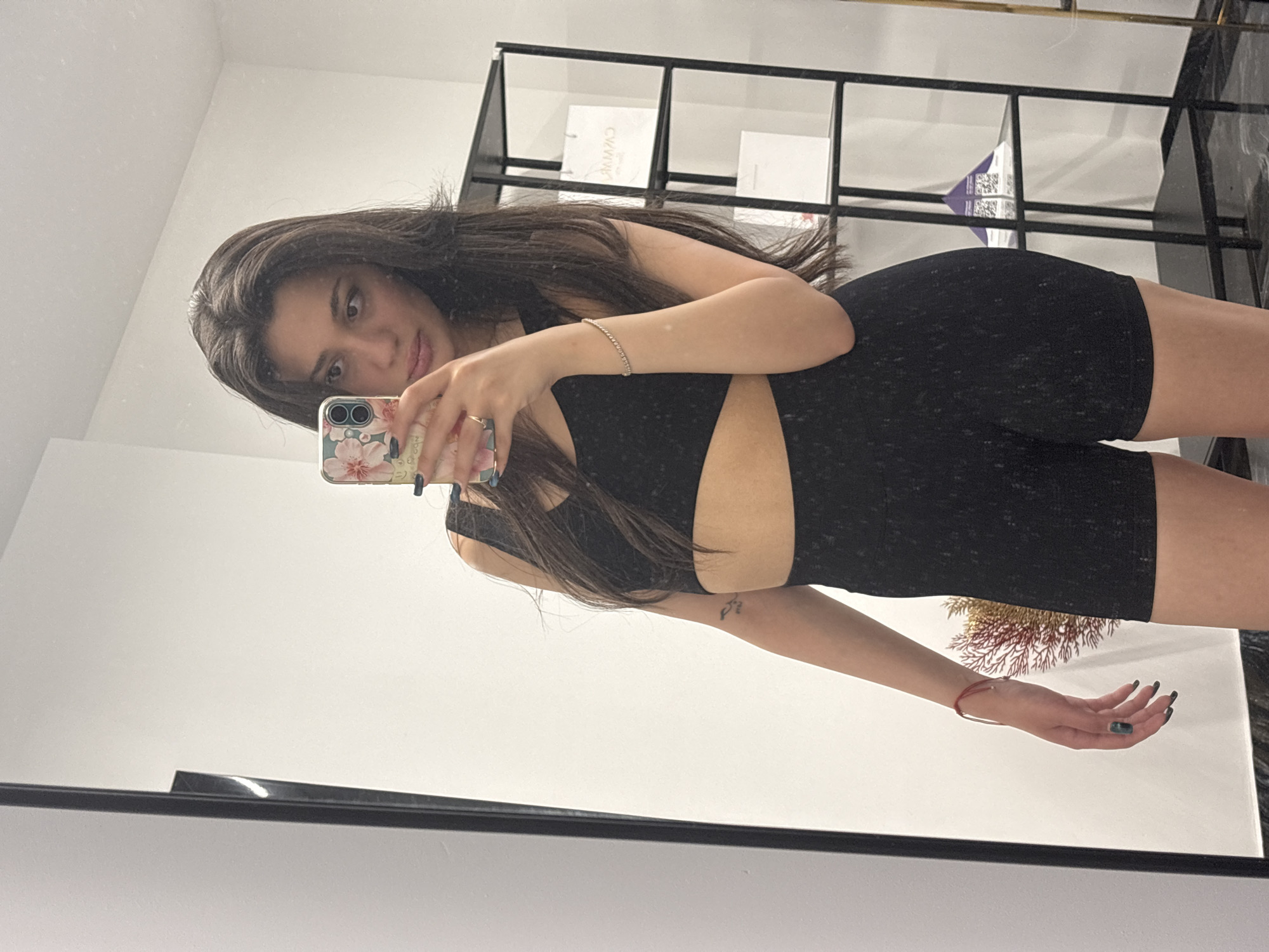 Woman takes mirror selfies in athletic wear, displays tattoo