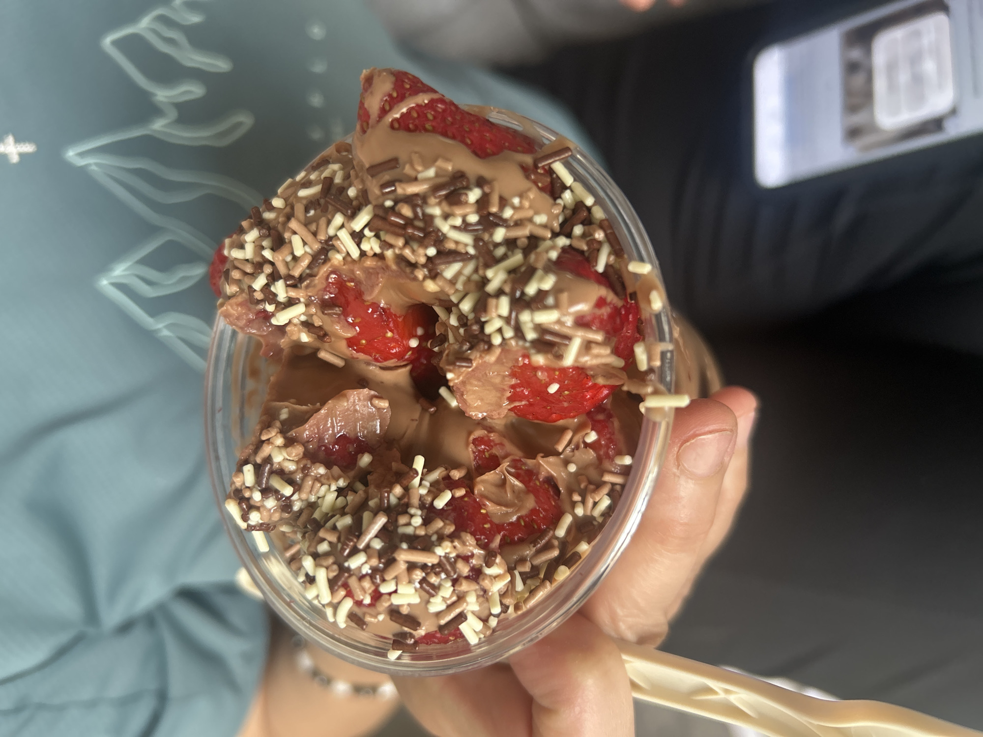 Person holds strawberry chocolate dessert cup with sprinkles