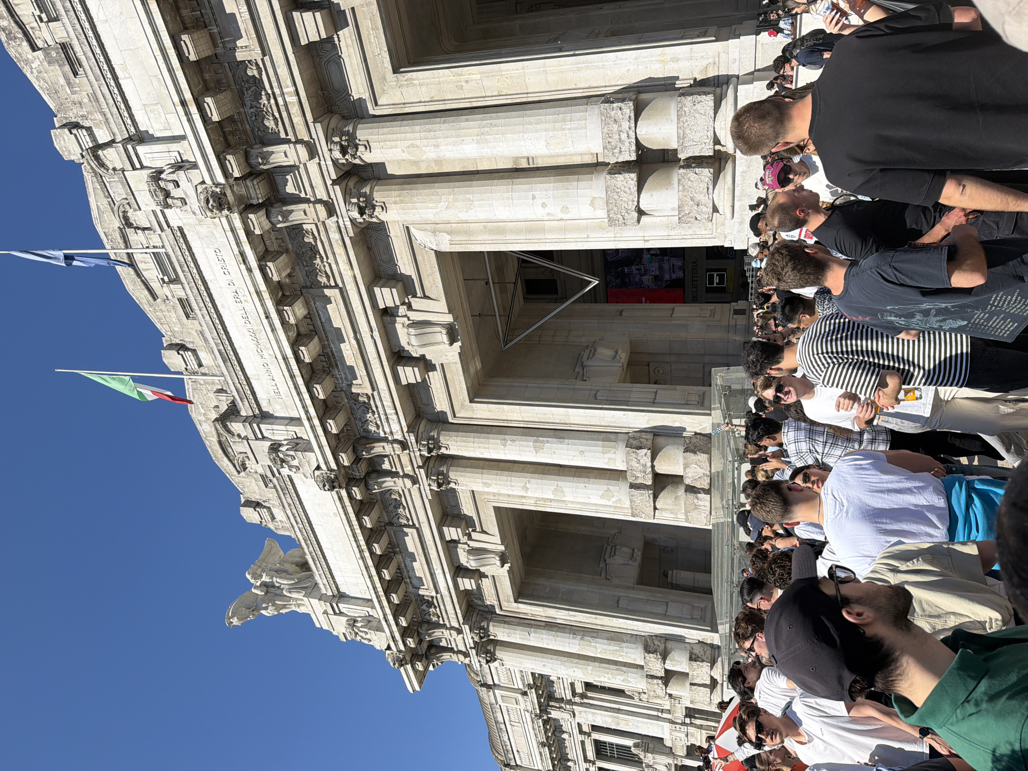 Crowds gather at Milan Central Station's neo-classical facade