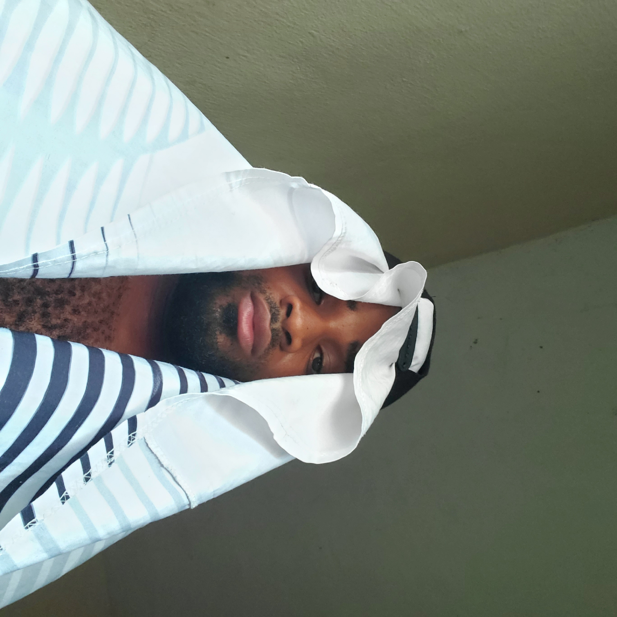 Man photographed under striped sheet in Obosi, Nigeria
