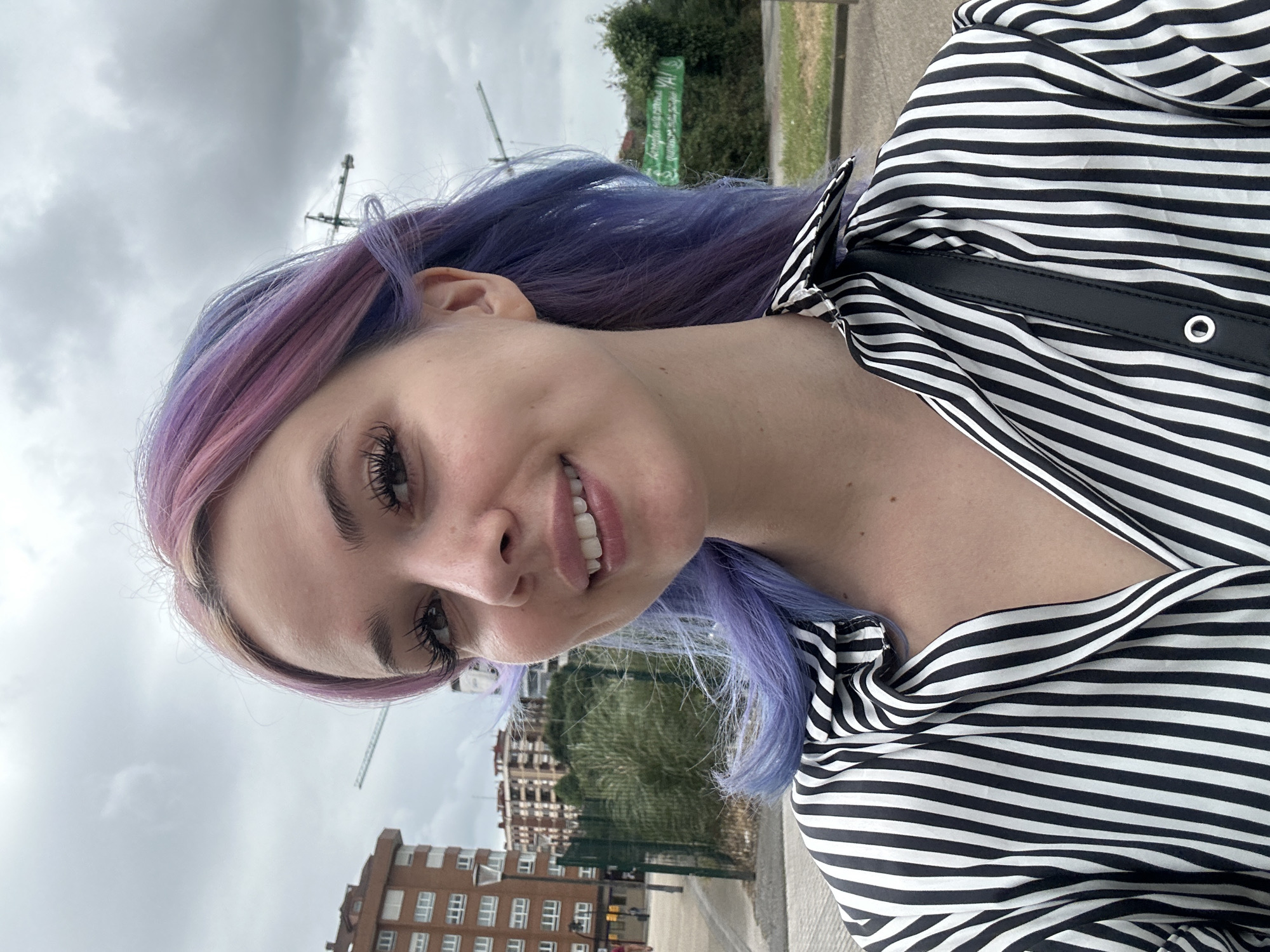 Woman takes colorful selfies in overcast Gijón cityscape