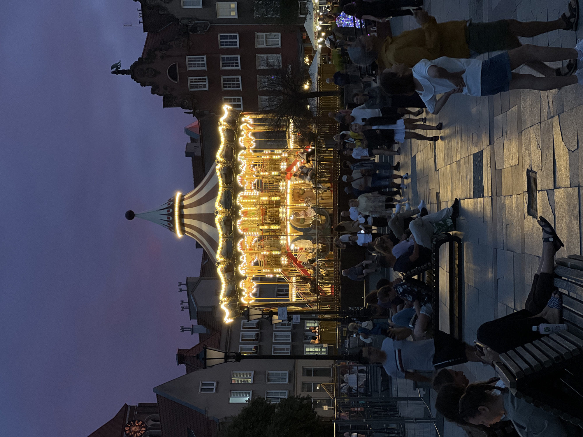 Lit carousel and evening foot traffic in Gdańsk's old town