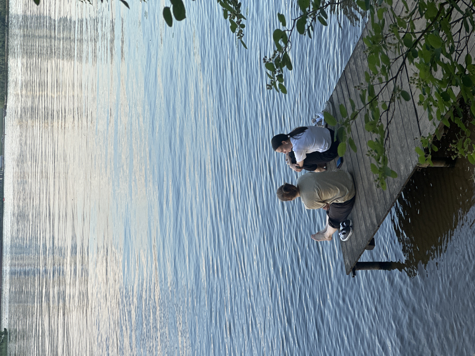 Two people sit on wooden dock in Moscow waterway