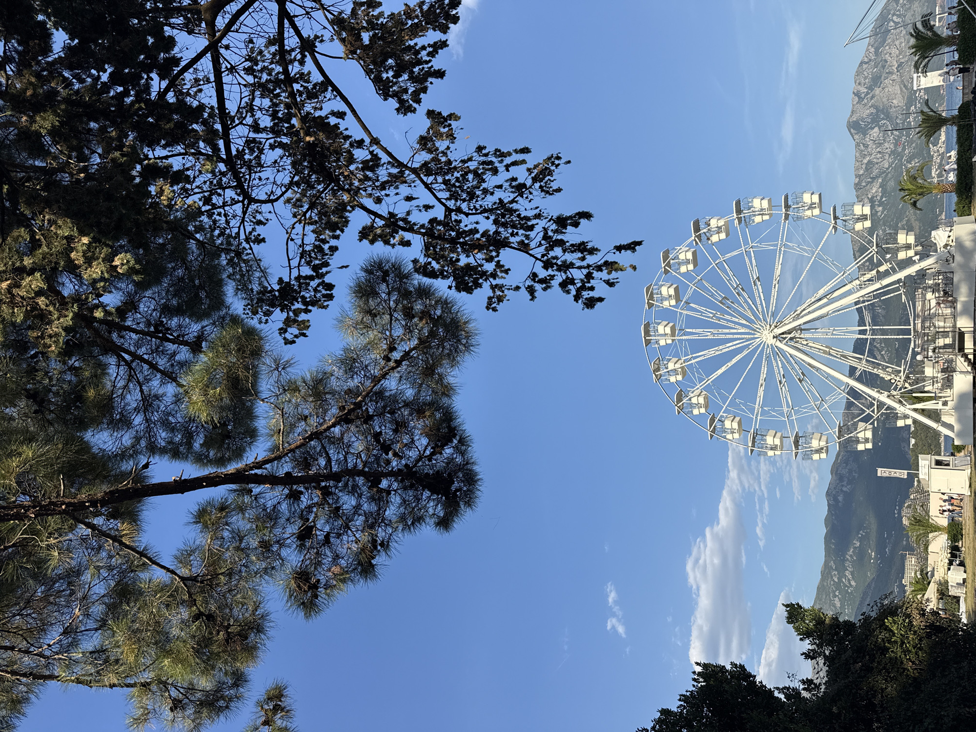 White Ferris wheel spinning with mountains and water behind it