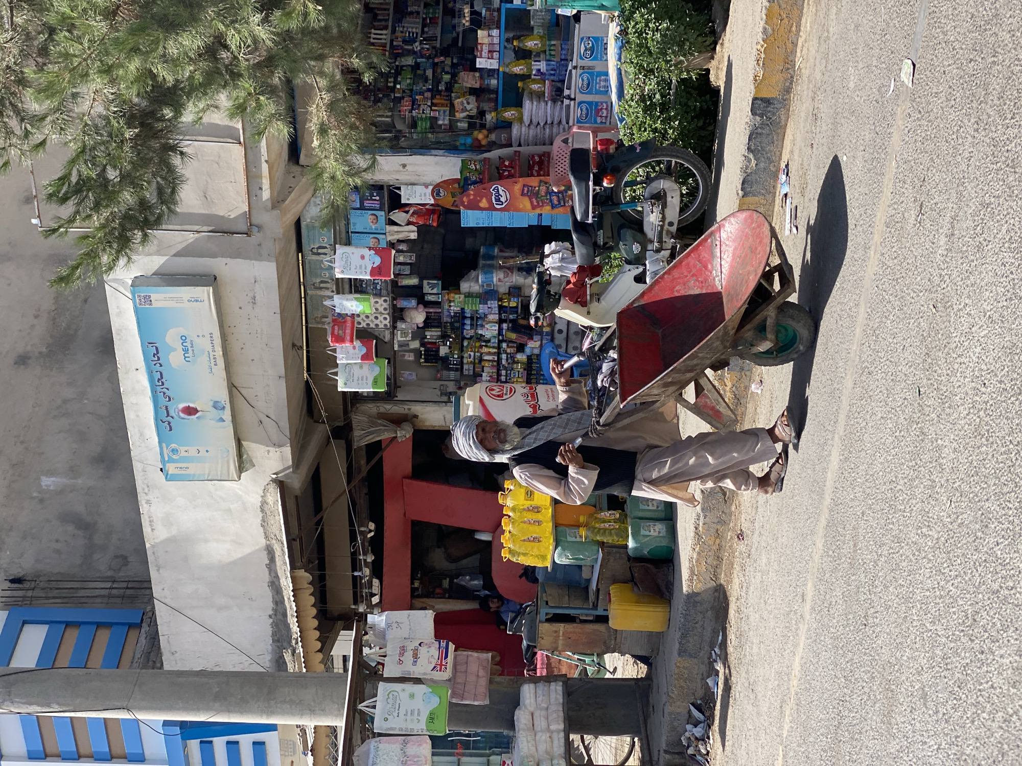 Red wheelbarrow loaded with goods moves through Kandahar streets